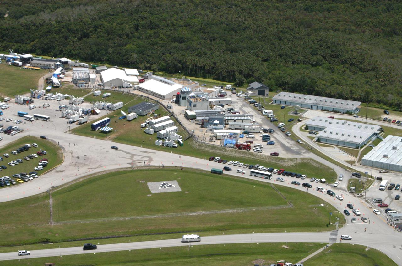 KENNEDY SPACE CENTER, FLA. - The Astrovan (on the road at the bottom center of photo), carrying the STS-114 crew, drives back from Launch Pad 39B after the scrub of the Return to Flight mission. The scrub was called due to a faulty sensor reading in the External Tank. The center of the photo shows the NASA News Center surrounded by trailers, satellite trucks and vehicles of the media covering the historic launch.