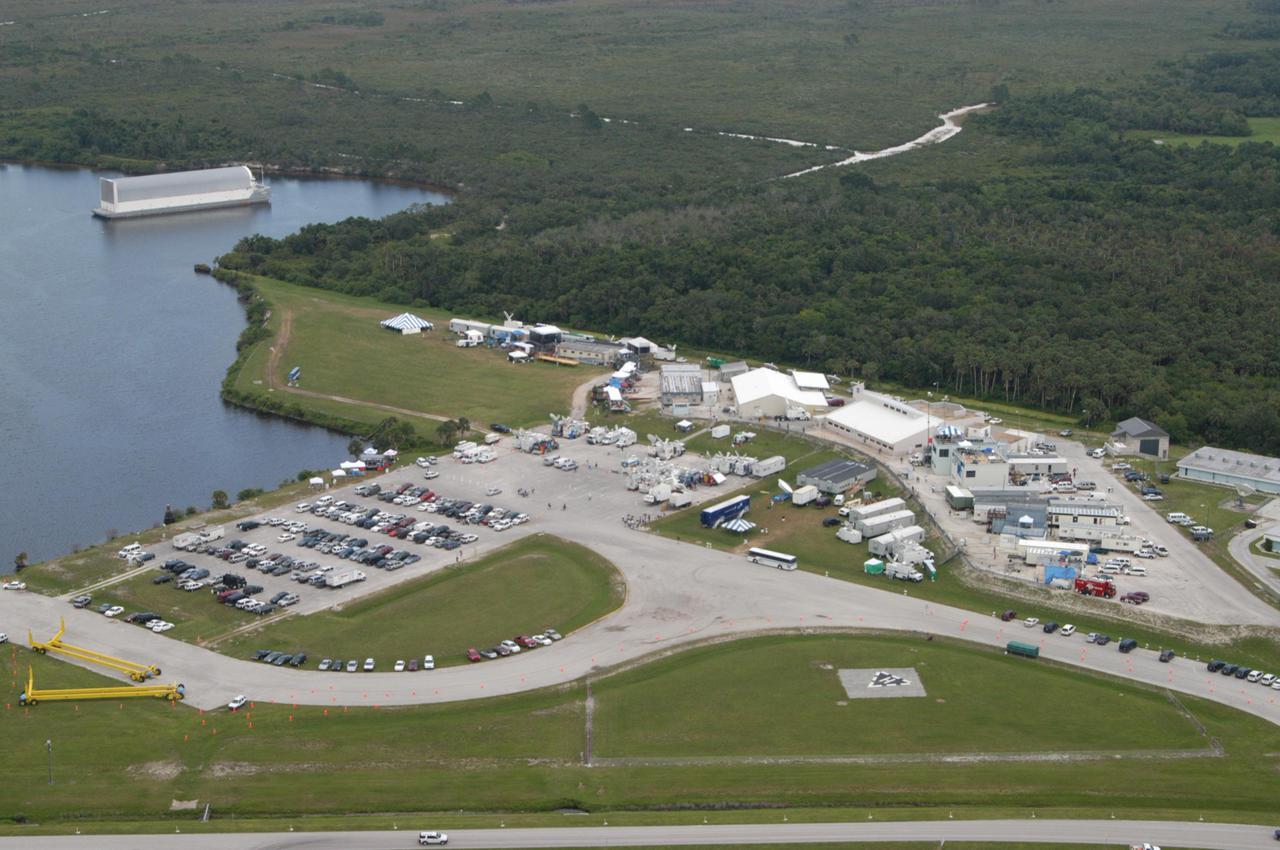 KENNEDY SPACE CENTER, FLA. -   A view from the Vehicle Assembly Building shows the NASA News Center surrounded by satellite trucks, trailers and buildings for the more than 1,000 media who converged on NASA’s Kennedy Space Center to cover the launch of Space Shuttle Discovery on Return to Flight mission STS-114.  In the water in the upper left is the barge that transports External Tanks from the Michoud Assembly Facility in New Orleans.