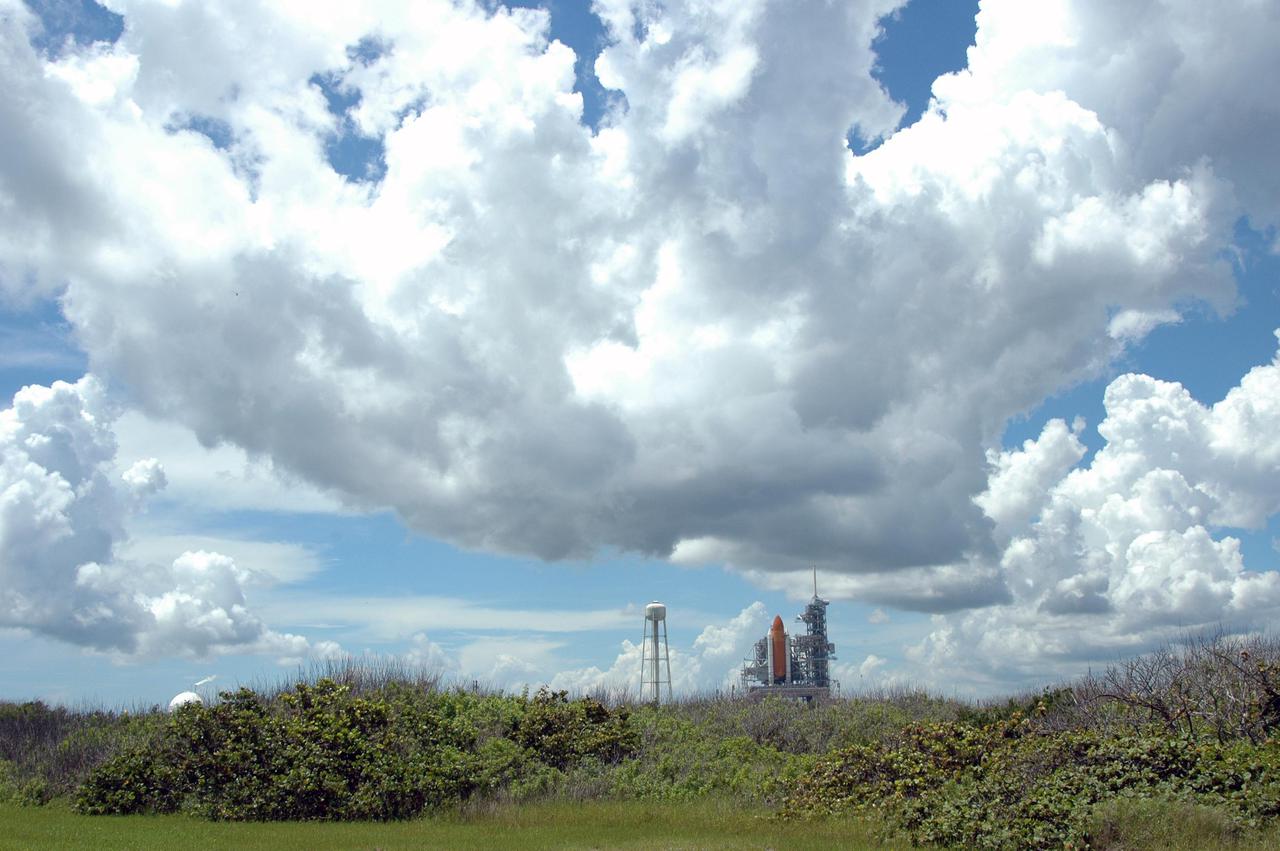 KENNEDY SPACE CENTER, FLA. -   Under evening cloud-filled skies, Space Shuttle Discovery remains on the pad two days after the Shuttle’s launch on Return to Flight mission STS-114 was scrubbed.  The July 13 mission was scrubbed when a low-level fuel cut-off sensor for the liquid hydrogen tank inside the External Tank failed a routine prelaunch check during the countdown July 13, causing mission managers to scrub Discovery's first launch attempt. The sensor protects the Shuttle's main engines by triggering their shutdown in the event fuel runs unexpectedly low. The sensor is one of four inside the liquid hydrogen section of the External Tank (ET).