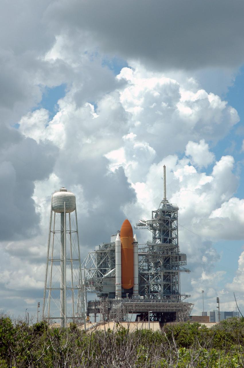 KENNEDY SPACE CENTER, FLA. - Space Shuttle Discovery remains on the pad the day after the Shuttle’s launch on Return to Flight mission STS-114 was scrubbed. The Rotating Service Structure has been closed. At left is the 290-foot-tall water tower that holds 300,000 gallons of water, part of the sound suppression system during a launch. Above the Shuttle at right is the 80-foot lightning mast. The July 13 mission was scrubbed when a low-level fuel cut-off sensor for the liquid hydrogen tank inside the External Tank failed a routine prelaunch check during the countdown July 13, causing mission managers to scrub Discovery's first launch attempt. The sensor protects the Shuttle's main engines by triggering their shutdown in the event fuel runs unexpectedly low. The sensor is one of four inside the liquid hydrogen section of the External Tank (ET).