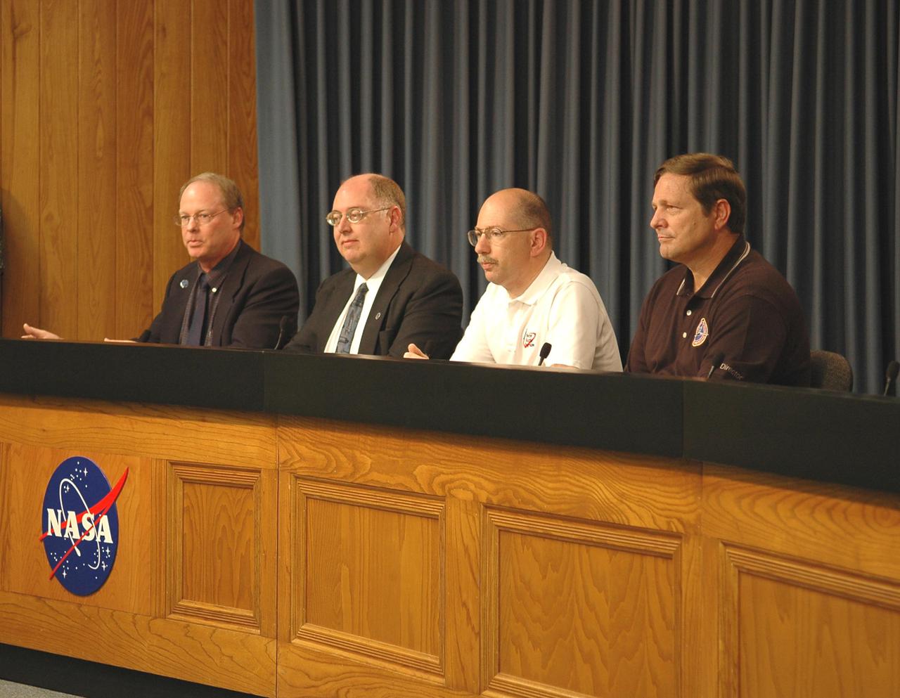 KENNEDY SPACE CENTER, FLA. -   At a press conference, members of the Mission Management Team reveal aspects of the troubleshooting and testing being done on the liquid hydrogen tank low-level fuel cut-off sensor. From left are moderator Bruce Buckingham, NASA news chief; Wayne Hale, Space Shuttle deputy program manager; John Muratore, manager of Systems Engineering and Integration for the Space Shuttle Program; and Mike Wetmore, director of Space Shuttle Processing. The sensor failed a routine prelaunch check during the launch countdown July 13, causing mission managers to scrub Discovery's first launch attempt. The sensor protects the Shuttle's main engines by triggering their shutdown in the event fuel runs unexpectedly low. The sensor is one of four inside the liquid hydrogen section of the External Tank (ET).