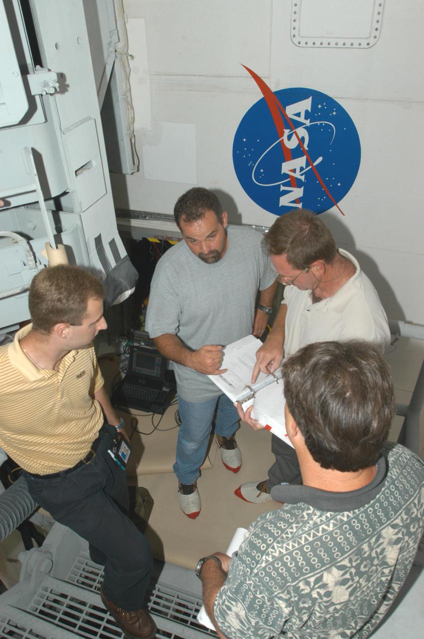 KENNEDY SPACE CENTER, FLA. -   After conducting electromagnetic interference and ground resistance testing on wiring in the aft engine compartment on Space Shuttle Discovery using various test equipment, such as current probes, amp meters, digital volt meters, breakout boxes, Nicollet recorders, oscilloscopes and time domain reflectometers, Aaron Sherman (left), Jack Colella (center) and Jeff Huet (lower right), all with United Space Alliance, and John Kennedy, NASA, review data.  Engineering teams have been working through a troubleshooting plan to address an issue with a liquid hydrogen low-level fuel sensor circuit. The sensor circuit failed a routine prelaunch check during the countdown July 13, delaying Discovery’s first launch attempt on Return to Flight mission STS-114.