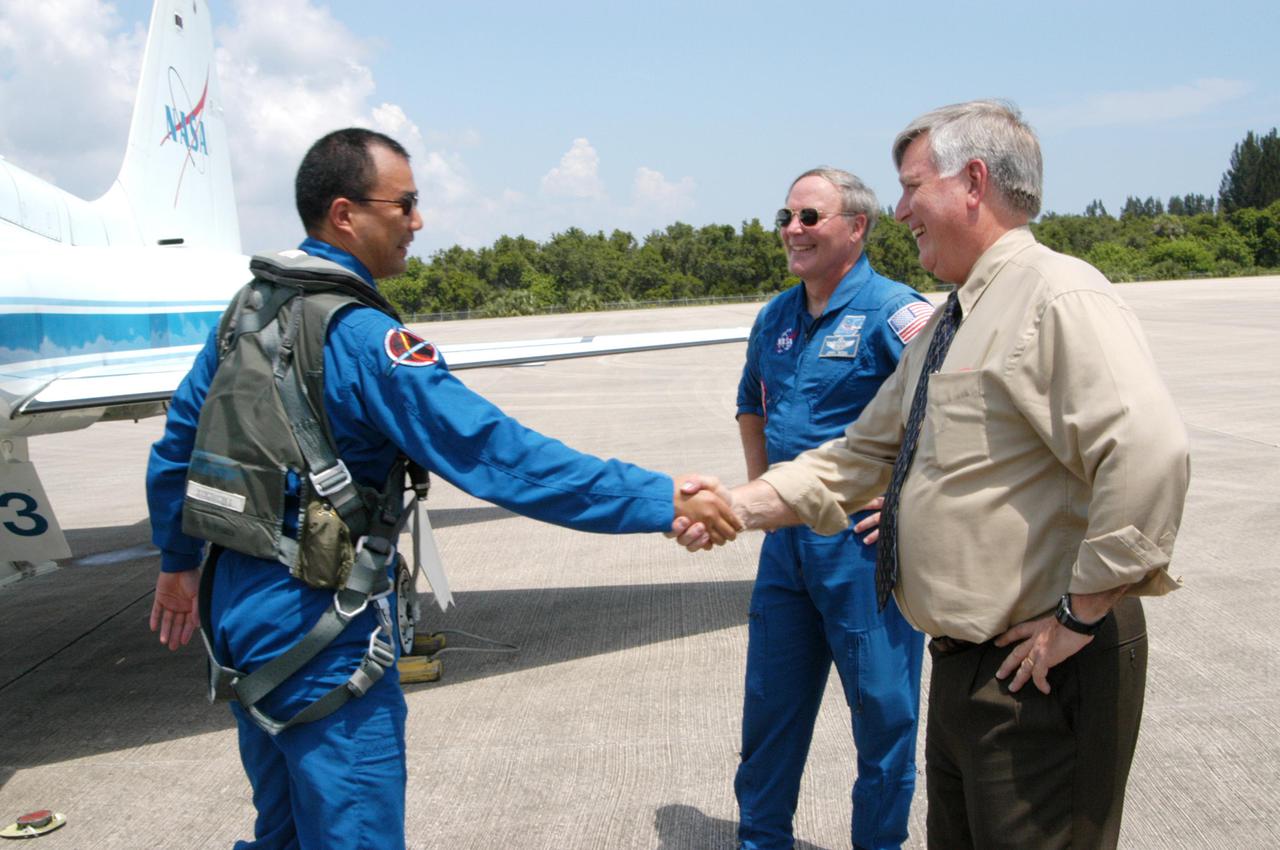 KENNEDY SPACE CENTER, FLA. - Center Director Jim Kennedy (right) greets STS-114 Mission Specialist Soichi Noguchi after his landing at NASA Kennedy Space Center. The Return to Flight STS-114 crew has returned to KSC to get ready for a second launch attempt aboard Space Shuttle Discovery. Behind Noguchi and Kennedy is astronaut Jerry Ross, who serves as chief of the Vehicle Integration Test Office at Johnson Space Center in Houston. Mission Commander Eileen Collins later told the media who waited nearby that since the scrub on July 13, the crew has focused on the on-orbit part of the mission and training for night landings using the Shuttle Training Aircraft. She praised the engineers and technicians who have been troubleshooting the elusive sensor problem and thanked them. STS-114 is scheduled to launch July 26 at 10:39 a.m. EDT from Launch Pad 39B.