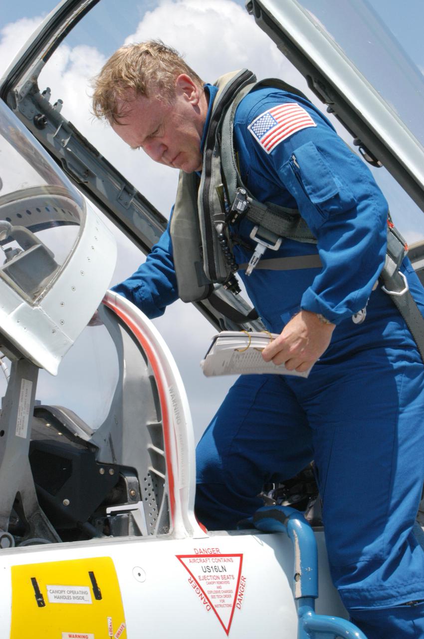 KENNEDY SPACE CENTER, FLA. -   STS-114 Mission Specialist Andrew Thomas climbs out of the T-38 jet aircraft on NASA Kennedy Space Center’s Shuttle Landing Facility.  The Return to Flight STS-114 crew has returned to KSC to get ready for a second launch attempt aboard Space Shuttle Discovery.  Mission Commander Eileen Collins later told the media who waited nearby that since the scrub on July 13, the crew has focused on the on-orbit part of the mission and training for night landings using the Shuttle Training Aircraft.  She praised the engineers and technicians who have been troubleshooting the elusive sensor problem and thanked them.  STS-114 is scheduled to launch July 26 at 10:39 a.m. EDT from Launch Pad 39B.