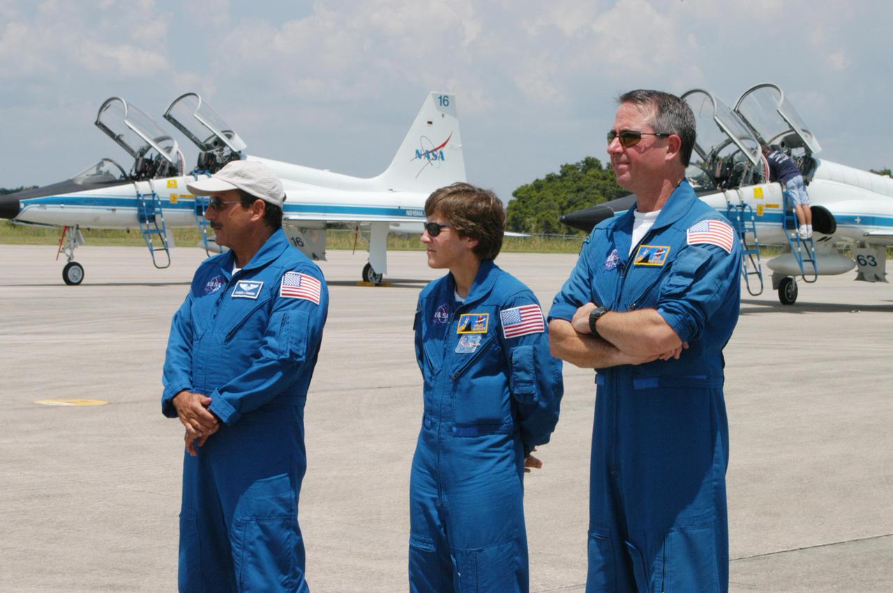 KENNEDY SPACE CENTER, FLA. - On NASA Kennedy Space Center’s Shuttle Landing Facility, the Return to Flight STS-114 crew waits while Mission Commander Eileen Collins talks to the media. Seen in the photo are (from left) Mission Specialists Charles Camarda, Wendy Lawrence and Stephen Robinson. Collins states that since the scrub on July 13, the crew has focused on the on-orbit part of the mission and training for night landings using the Shuttle Training Aircraft. She praised the engineers and technicians who have been troubleshooting the elusive sensor problem and thanked them. STS-114 is scheduled to launch July 26 at 10:39 a.m. EDT from Launch Pad 39B.