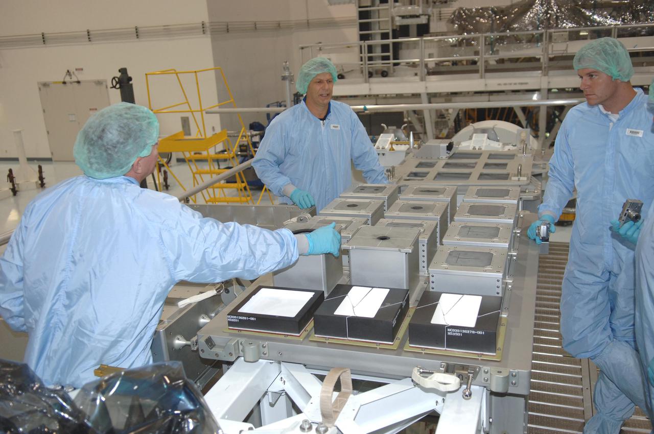 KENNEDY SPACE CENTER, FLA. - In the Space Station Processing Facility at NASA Kennedy Space Center, STS-121 Mission Specialist Piers Sellers (center) works with the Detailed Test Objective (DTO) tile sample repair kit situated on the Lightweight Multi-Purpose Experiment Support Structure Carrier (LMC). The STS-121 crew is at KSC to take part in Crew Equipment Interface Test activities, which provide hands-on experience with equipment they will use on-orbit. STS-121, the second Return to Flight mission, is targeted for launch in a lighted planning window of Sept. 9 to Sept. 25.