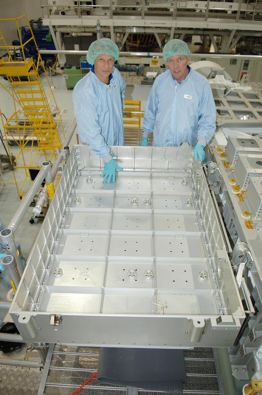 KENNEDY SPACE CENTER, FLA. - In the Space Station Processing Facility at NASA Kennedy Space Center, STS-121 Mission Specialists Piers Sellers (left) and Michael Fossum look at the Detailed Test Objective (DTO) tile sample repair kit situated on the Lightweight Multi-Purpose Experiment Support Structure Carrier (LMC). The STS-121 crew is at KSC to take part in Crew Equipment Interface Test activities, which provide hands-on experience with equipment they will use on-orbit. STS-121, the second Return to Flight mission, is targeted for launch in a lighted planning window of Sept. 9 to Sept. 25.