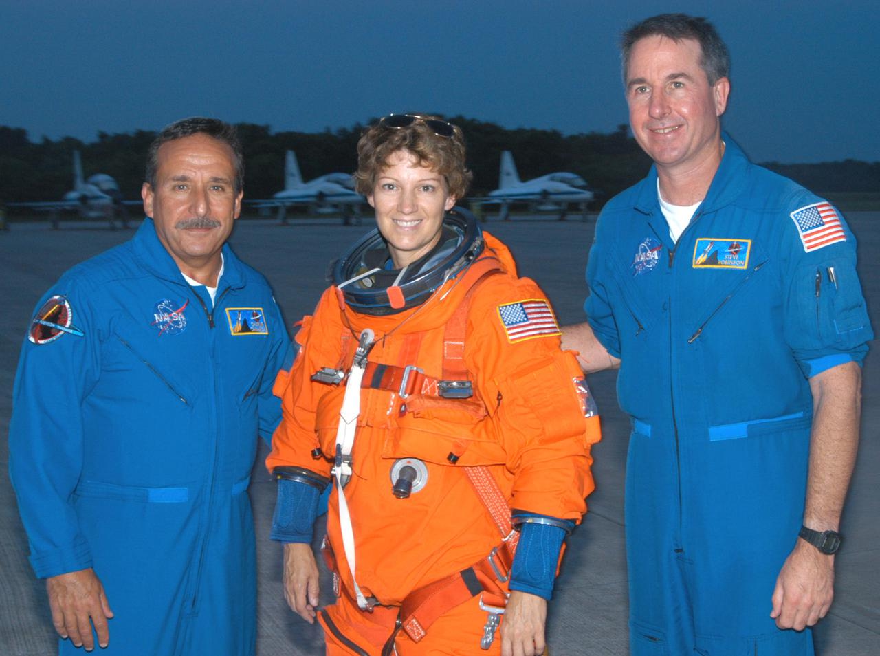 KENNEDY SPACE CENTER, FLA. - At the Shuttle Landing Facility on NASA Kennedy Space Center, STS-114 Mission Commander Eileen Collins pauses for a photo with fellow crew members. At left is Mission Specialist Charles Camarda; at right is Mission Specialist Stephen Robinson. Collins and Pilot James Kelly have been practicing night landings in the Shuttle Training Aircraft (STA) in preparation for the mission. The STA is a modified Grumman American Aviation-built Gulf Stream II executive jet that was modified to simulate an orbiter’s cockpit, motion and visual cues, and handling qualities. In flight, the STA duplicates the orbiter’s atmospheric descent trajectory from approximately 35,000 feet altitude to landing on a runway. Because the orbiter is unpowered during re-entry and landing, its high-speed glide must be perfectly executed the first time. Return to Flight Mission STS-114 is scheduled to launch aboard Space Shuttle Discovery with a crew of seven at 10:39 a.m. EDT on July 26. Landing is expected on Aug. 7.