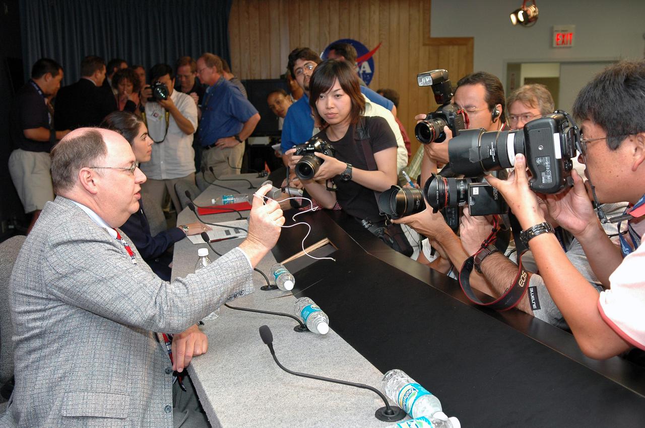 KENNEDY SPACE CENTER, FLA. - After the STS-114 Launch Readiness Press Conference at NASA Kennedy Space Center, media crowd around Space Shuttle Deputy Program Manager Wayne Hale, who is holding an ECO (engine cut-off) sensor similar to the one in the External Tank that had a faulty reading in the first launch attempt.   Liftoff of Space Shuttle Discovery on the Return to Flight mission STS-114 is scheduled for 10:39 a.m. EDT July 26 from Launch Pad 39B.
