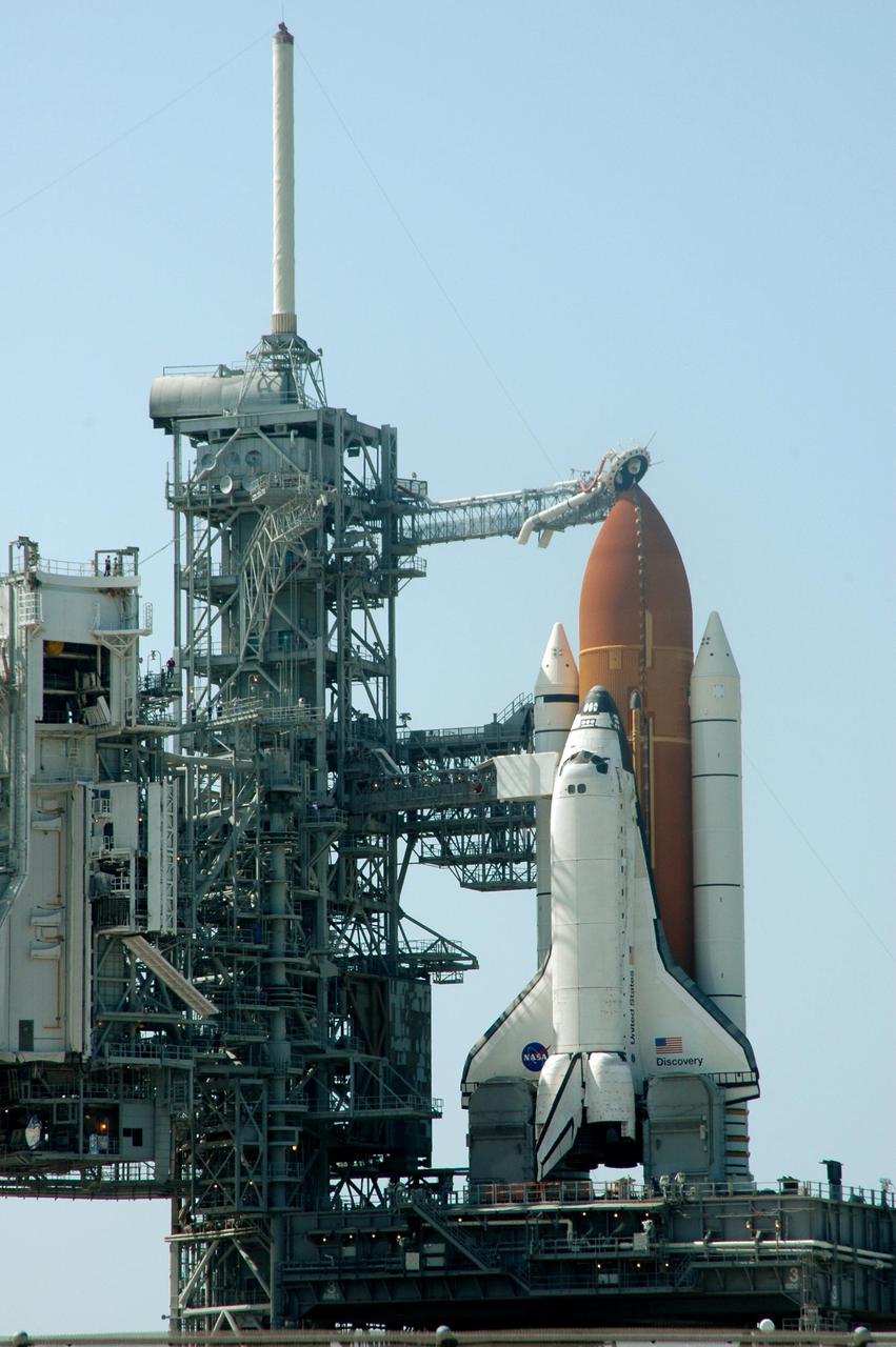 KENNEDY SPACE CENTER, FLA. - Space Shuttle Discovery in full launch configuration is revealed after the Rotating Service Structure (RSS) is rotated back at Launch Pad 39B at NASA Kennedy Space Center.  The gaseous oxygen vent arm (beanie cap) has been extended to the top of the External Tank.  Rollback of the RSS is a major preflight milestone, typically occurring during the T-11-hour hold on L-1 (the day before launch). Discovery is scheduled to lift off on the historic Return to Flight mission STS-114 at 10:39 a.m. EDT July 26 with a crew of seven.  On the mission to the International Space Station the crew will perform inspections on orbit for the first time of all of the Reinforced Carbon-Carbon (RCC) panels on the leading edge of the wings and the Thermal Protection System tiles using the new Canadian-built Orbiter Boom Sensor System and the data from 176 impact and temperature sensors. Mission Specialists will also practice repair techniques on RCC and tile samples during a spacewalk in the payload bay.  During two additional spacewalks, the crew will install the External Stowage Platform-2, equipped with spare part assemblies, and a replacement Control Moment Gyroscope contained in the Lightweight Multi-Purpose Experiment Support Structure.