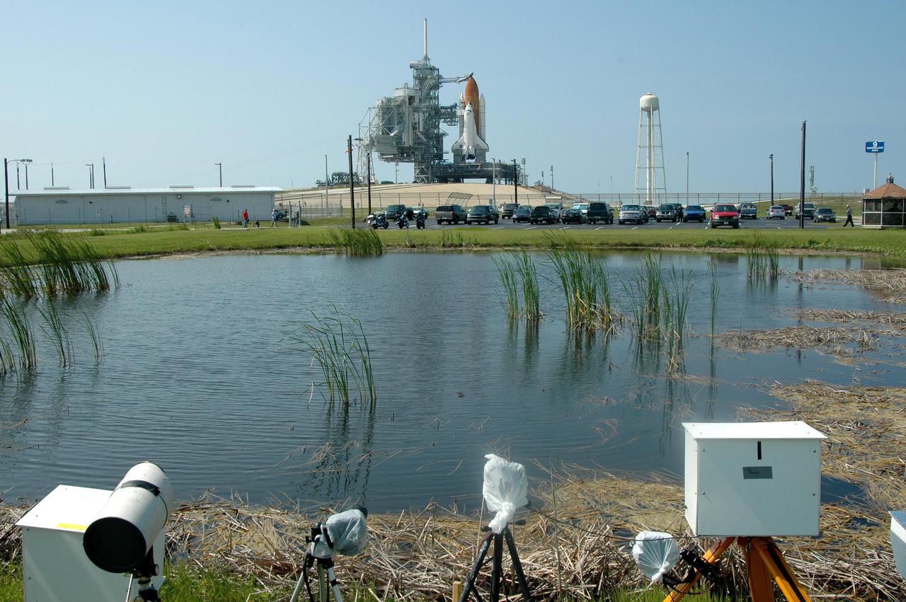 KENNEDY SPACE CENTER, FLA. - Cameras at the edge of a pond have a pristine view to Launch Pad 39B at NASA Kennedy Space Center where the Space Shuttle Discovery waits for launch.  On the right of the Shuttle is the 290-foot-tall water tower that holds 300,000 gallons of water, part of the sound suppression system during a launch.  Discovery is scheduled to lift off on the historic Return to Flight mission STS-114 at 10:39 a.m. EDT July 26 with a crew of seven.  On the mission to the International Space Station the crew will perform inspections on orbit for the first time of all of the Reinforced Carbon-Carbon (RCC) panels on the leading edge of the wings and the Thermal Protection System tiles using the new Canadian-built Orbiter Boom Sensor System and the data from 176 impact and temperature sensors. Mission Specialists will also practice repair techniques on RCC and tile samples during a spacewalk in the payload bay.  During two additional spacewalks, the crew will install the External Stowage Platform-2, equipped with spare part assemblies, and a replacement Control Moment Gyroscope contained in the Lightweight Multi-Purpose Experiment Support Structure.