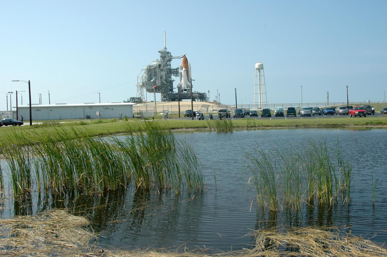 KENNEDY SPACE CENTER, FLA. - At the edge of a pond across from Launch Pad 39B, only long grasses stand between the camera and Space Shuttle Discovery as it waits for launch. Discovery is scheduled to lift off on the historic Return to Flight mission STS-114 at 10:39 a.m. EDT July 26 with a crew of seven. On the mission to the International Space Station the crew will perform inspections on orbit for the first time of all of the Reinforced Carbon-Carbon (RCC) panels on the leading edge of the wings and the Thermal Protection System tiles using the new Canadian-built Orbiter Boom Sensor System and the data from 176 impact and temperature sensors. Mission Specialists will also practice repair techniques on RCC and tile samples during a spacewalk in the payload bay. During two additional spacewalks, the crew will install the External Stowage Platform-2, equipped with spare part assemblies, and a replacement Control Moment Gyroscope contained in the Lightweight Multi-Purpose Experiment Support Structure.