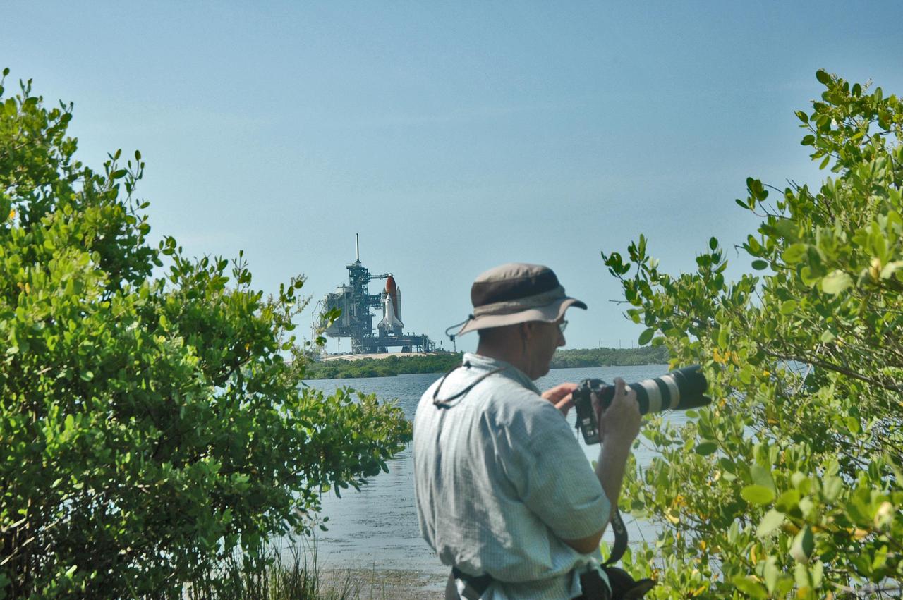 KENNEDY SPACE CENTER, FLA. - This professional photographer is one of hundreds who are gathered at NASA Kennedy Space Center to capture the historic launch of Space Shuttle Discovery, seen on Launch Pad 39B on the horizon.  Discovery is scheduled to lift off on the historic Return to Flight mission STS-114 at 10:39 a.m. EDT July 26 with a crew of seven.  On the mission to the International Space Station the crew will perform inspections on orbit for the first time of all of the Reinforced Carbon-Carbon (RCC) panels on the leading edge of the wings and the Thermal Protection System tiles using the new Canadian-built Orbiter Boom Sensor System and the data from 176 impact and temperature sensors. Mission Specialists will also practice repair techniques on RCC and tile samples during a spacewalk in the payload bay.  During two additional spacewalks, the crew will install the External Stowage Platform-2, equipped with spare part assemblies, and a replacement Control Moment Gyroscope contained in the Lightweight Multi-Purpose Experiment Support Structure.