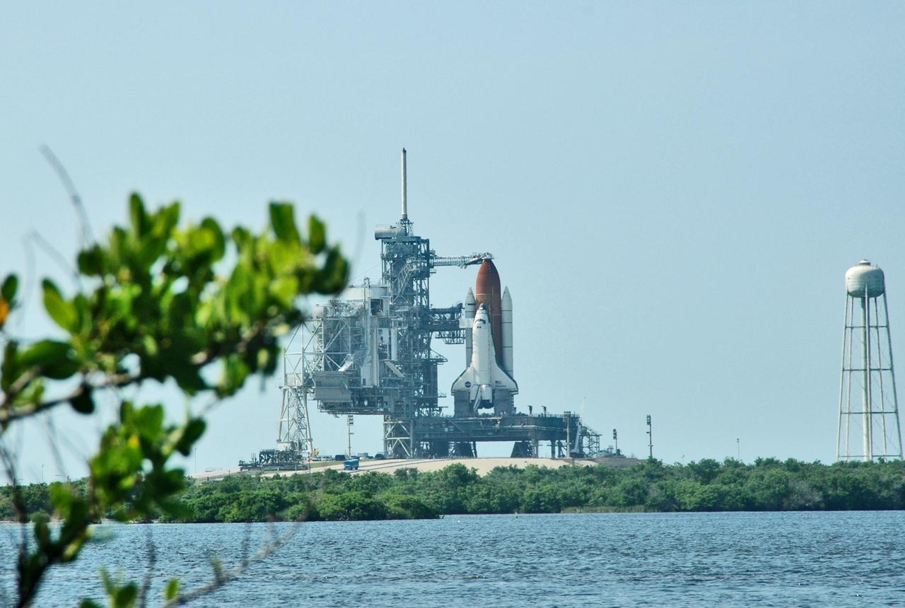 KENNEDY SPACE CENTER, FLA. - Seen after rollback of the Rotating Service Structure, and framed by marsh greenery, a fully revealed Space Shuttle Discovery on NASA Kennedy Space Center’s Launch Pad 39B erupts on the horizon beyond the pond.   Discovery is scheduled to lift off on the historic Return to Flight mission STS-114 at 10:39 a.m. EDT July 26 with a crew of seven.  On the mission to the International Space Station the crew will perform inspections on orbit for the first time of all of the Reinforced Carbon-Carbon (RCC) panels on the leading edge of the wings and the Thermal Protection System tiles using the new Canadian-built Orbiter Boom Sensor System and the data from 176 impact and temperature sensors. Mission Specialists will also practice repair techniques on RCC and tile samples during a spacewalk in the payload bay.  During two additional spacewalks, the crew will install the External Stowage Platform-2, equipped with spare part assemblies, and a replacement Control Moment Gyroscope contained in the Lightweight Multi-Purpose Experiment Support Structure.