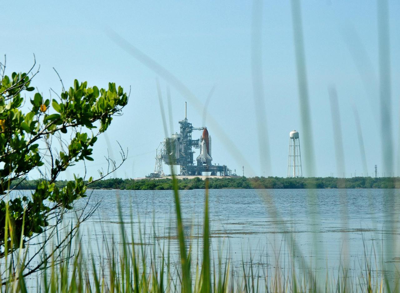 KENNEDY SPACE CENTER, FLA. - At the edge of a pond across from Launch Pad 39B, only long grasses stand between the camera and Space Shuttle Discovery as it waits for launch. Discovery is scheduled to lift off on the historic Return to Flight mission STS-114 at 10:39 a.m. EDT July 26 with a crew of seven. On the mission to the International Space Station the crew will perform inspections on orbit for the first time of all of the Reinforced Carbon-Carbon (RCC) panels on the leading edge of the wings and the Thermal Protection System tiles using the new Canadian-built Orbiter Boom Sensor System and the data from 176 impact and temperature sensors. Mission Specialists will also practice repair techniques on RCC and tile samples during a spacewalk in the payload bay. During two additional spacewalks, the crew will install the External Stowage Platform-2, equipped with spare part assemblies, and a replacement Control Moment Gyroscope contained in the Lightweight Multi-Purpose Experiment Support Structure.