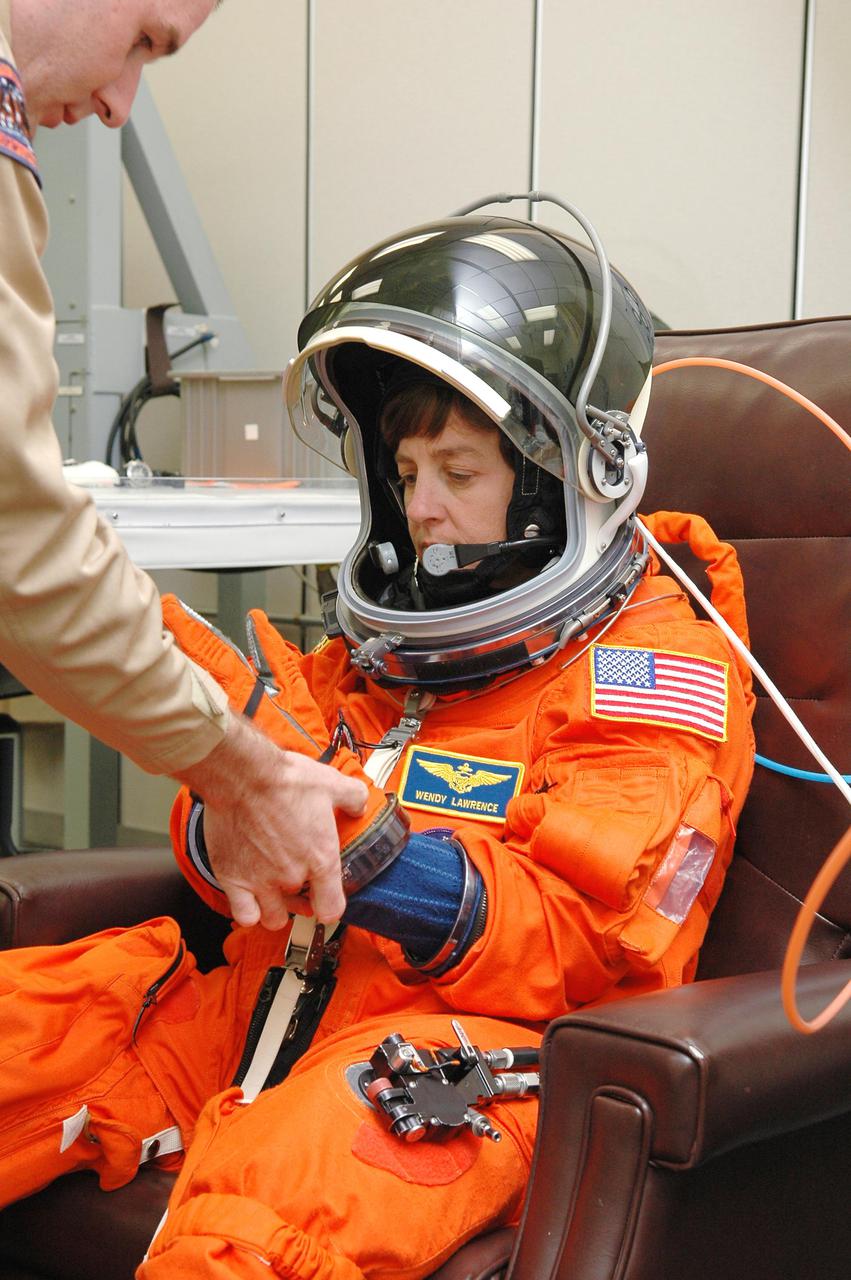 KENNEDY SPACE CENTER, FLA. -  In the Operations and Checkout Building at NASA Kennedy Space Center, STS-114 Mission Specialist Wendy Lawrence is helped putting on the gloves to the launch and entry suit before heading to the launch pad.  Lawrence is making her fourth space flight on the historic Return to Flight mission STS-114 to the International Space Station.  On its second attempt for launch, Discovery is scheduled to lift off at 10:39 a.m. EDT today from Launch Pad 39B.  It is the 114th Space Shuttle flight and the 31st for Discovery.  The 12-day mission is expected to end with touchdown at the Shuttle Landing Facility on Aug. 7.