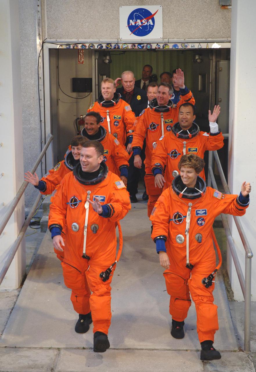 KENNEDY SPACE CENTER, FLA. -  The Return to Flight STS-114 crew exits the Operations and Checkout Building, heading for the bus that will transport them to Launch Pad 39B.  On the left, front to back, are Pilot James Kelly and Mission Specialists Wendy Lawrence, Charles Camarda and Andrew Thomas.  On the right, front to back, are Mission Commander Eileen Collins and Mission Specialists Soichi Noguchi and Stephen Robinson.  Noguchi represents the Japan Aerospace Exploration Agency.  On its second attempt for launch, Discovery is scheduled to lift off at 10:39 a.m. EDT today from Launch Pad 39B.  It is the 114th Space Shuttle flight and the 31st for Discovery.  The 12-day mission is expected to end with touchdown at the Shuttle Landing Facility on Aug. 7.  On this mission to the International Space Station the crew will perform inspections on-orbit for the first time of all of the Reinforced Carbon-Carbon (RCC) panels on the leading edge of the wings and the Thermal Protection System tiles using the new Canadian-built Orbiter Boom Sensor System and the data from 176 impact and temperature sensors. Mission Specialists will also practice repair techniques on RCC and tile samples during a spacewalk in the payload bay.  During two additional spacewalks, the crew will install the External Stowage Platform-2, equipped with spare part assemblies, and a replacement Control Moment Gyroscope contained in the Lightweight Multi-Purpose Experiment Support Structure.