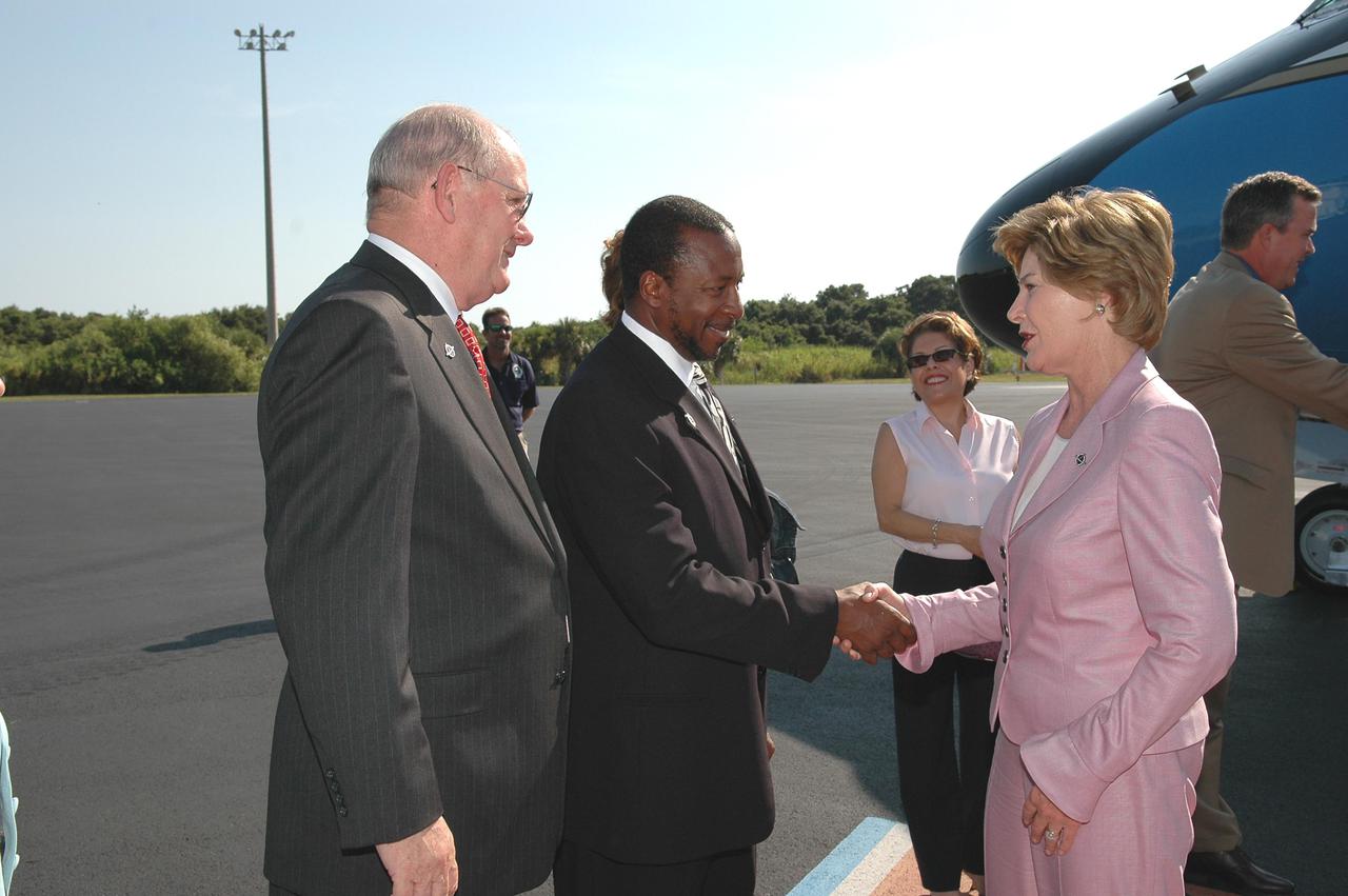 KENNEDY SPACE CENTER, FLA. - After arriving at the Skid Strip on Cape Canaveral Air Force Station, First Lady Laura Bush is welcomed by Jim Hattaway (left), associate director at NASA Kennedy Space Center, and Woodrow Whitlow Jr., deputy director at KSC. Mrs. Bush is attending the historic launch of Space Shuttle Discovery on Return to Flight mission STS-114, scheduled to lift off at 10:39 a.m. EDT from Launch Pad 39B with a crew of seven. Mrs. Bush is only the third First Lady to witness a Space Shuttle launch at KSC. On this mission to the International Space Station the crew will perform inspections on-orbit for the first time of all of the Reinforced Carbon-Carbon (RCC) panels on the leading edge of the wings and the Thermal Protection System tiles using the new Canadian-built Orbiter Boom Sensor System and the data from 176 impact and temperature sensors. Mission Specialists will also practice repair techniques on RCC and tile samples during a spacewalk in the payload bay. During two additional spacewalks, the crew will install the External Stowage Platform-2, equipped with spare part assemblies, and a replacement Control Moment Gyroscope contained in the Lightweight Multi-Purpose Experiment Support Structure. The 12-day mission is expected to end with touchdown at the Shuttle Landing Facility on Aug. 7.