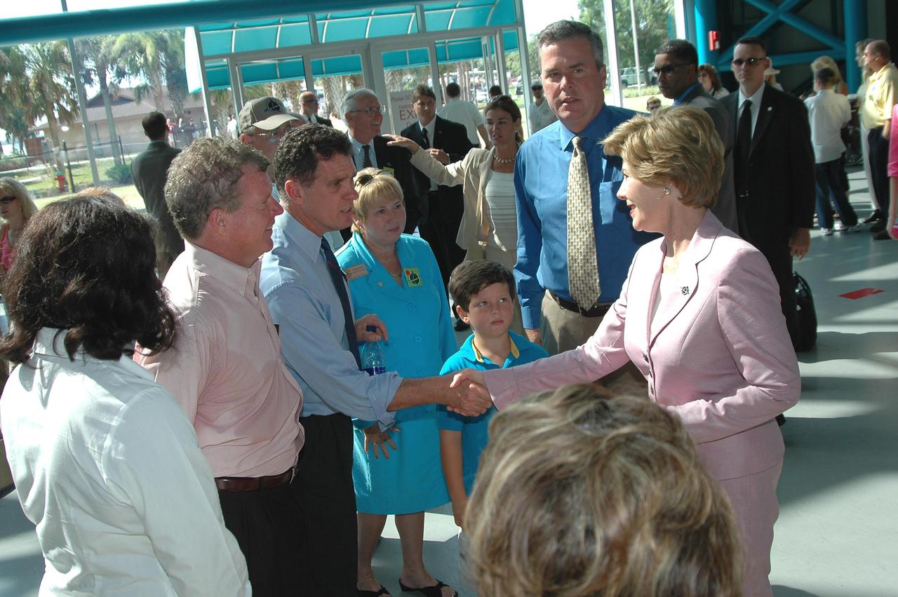 KENNEDY SPACE CENTER, FLA. - At NASA Kennedy Space Center’s Apollo_Saturn V Center, First Lady Laura Bush (right) greets Florida Congressman Dave Weldon (shaking hands) and Congressman Tom Feeney. They are attending the historic launch of Space Shuttle Discovery on Return to Flight mission STS-114, scheduled to lift off at 10:39 a.m. EDT from Launch Pad 39B with a crew of seven. Mrs. Bush is only the third First Lady to witness a Space Shuttle launch at KSC. Behind Mrs. Bush is Florida Gov. Jeb Bush. On this mission to the International Space Station the crew will perform inspections on-orbit for the first time of all of the Reinforced Carbon-Carbon (RCC) panels on the leading edge of the wings and the Thermal Protection System tiles using the new Canadian-built Orbiter Boom Sensor System and the data from 176 impact and temperature sensors. Mission Specialists will also practice repair techniques on RCC and tile samples during a spacewalk in the payload bay. During two additional spacewalks, the crew will install the External Stowage Platform-2, equipped with spare part assemblies, and a replacement Control Moment Gyroscope contained in the Lightweight Multi-Purpose Experiment Support Structure. The 12-day mission is expected to end with touchdown at the Shuttle Landing Facility on Aug. 7.