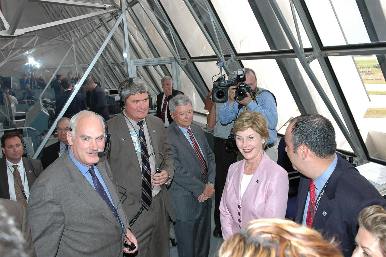 KENNEDY SPACE CENTER, FLA. -   In the Launch Control Center at NASA Kennedy Space Center, First Lady Laura Bush congratulates NASA officials for a successful launch of Space Shuttle Discovery on Return to Flight mission STS-114.  At left are Associate Administrator for Space Operations William Readdy and Space Shuttle Program Manager Bill Parsons.. On this mission to the International Space Station the crew will perform inspections on-orbit for the first time of all of the Reinforced Carbon-Carbon (RCC) panels on the leading edge of the wings and the Thermal Protection System tiles using the new Canadian-built Orbiter Boom Sensor System and the data from 176 impact and temperature sensors. Mission Specialists will also practice repair techniques on RCC and tile samples during a spacewalk in the payload bay.  During two additional spacewalks, the crew will install the External Stowage Platform-2, equipped with spare part assemblies, and a replacement Control Moment Gyroscope contained in the Lightweight Multi-Purpose Experiment Support Structure. The 12-day mission is expected to end with touchdown at the Shuttle Landing Facility on Aug. 7.