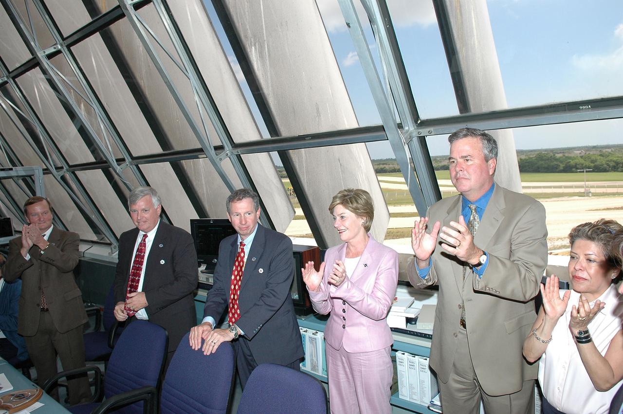 KENNEDY SPACE CENTER, FLA. -  In the Launch Control Center at NASA Kennedy Space Center, First Lady Laura Bush congratulates the launch team for a successful launch of Space Shuttle Discovery on Return to Flight mission STS-114.  From left are Shuttle Launch Director Mike Leinbach, Center Director Jim Kennedy, NASA Administrator Mike Griffin, Mrs. Bush, Florida Gov. Jeb Bush and his wife, Columba.   On this mission to the International Space Station the crew will perform inspections on-orbit for the first time of all of the Reinforced Carbon-Carbon (RCC) panels on the leading edge of the wings and the Thermal Protection System tiles using the new Canadian-built Orbiter Boom Sensor System and the data from 176 impact and temperature sensors. Mission Specialists will also practice repair techniques on RCC and tile samples during a spacewalk in the payload bay.  During two additional spacewalks, the crew will install the External Stowage Platform-2, equipped with spare part assemblies, and a replacement Control Moment Gyroscope contained in the Lightweight Multi-Purpose Experiment Support Structure. The 12-day mission is expected to end with touchdown at the Shuttle Landing Facility on Aug. 7.
