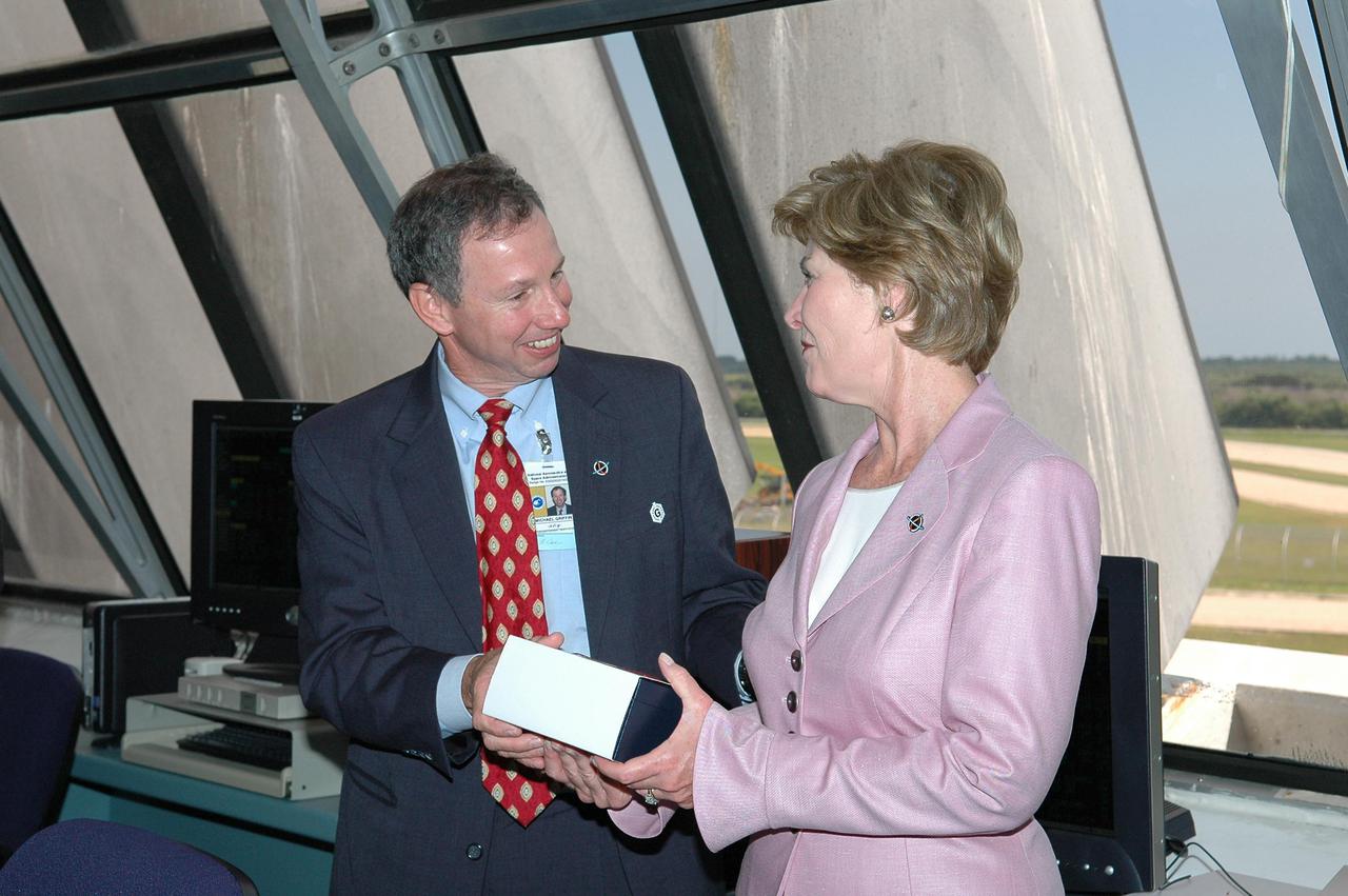 KENNEDY SPACE CENTER, FLA. - In the Launch Control Center at NASA Kennedy Space Center, NASA Administrator Mike Griffin (left) presents a gift to First Lady Laura Bush on the occasion of her first Space Shuttle launch.  She witnessed the historic launch of Space Shuttle Discovery on Return to Flight mission STS-114.  On this mission to the International Space Station the crew will perform inspections on-orbit for the first time of all of the Reinforced Carbon-Carbon (RCC) panels on the leading edge of the wings and the Thermal Protection System tiles using the new Canadian-built Orbiter Boom Sensor System and the data from 176 impact and temperature sensors. Mission Specialists will also practice repair techniques on RCC and tile samples during a spacewalk in the payload bay.  During two additional spacewalks, the crew will install the External Stowage Platform-2, equipped with spare part assemblies, and a replacement Control Moment Gyroscope contained in the Lightweight Multi-Purpose Experiment Support Structure. The 12-day mission is expected to end with touchdown at the Shuttle Landing Facility on Aug. 7.