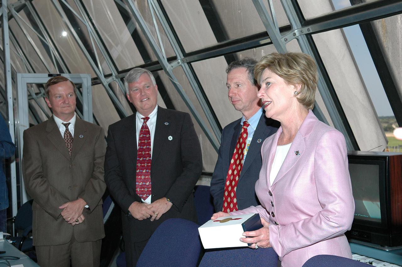 KENNEDY SPACE CENTER, FLA. - In the Launch Control Center at NASA Kennedy Space Center, First Lady Laura Bush talks to the launch team after the successful launch of Space Shuttle Discovery on Return to Flight mission STS-114.  NASA officials with her are, from left, Shuttle Launch Director Mike Leinbach, Center Director Jim Kennedy and NASA Administrator Mike Griffin. On this mission to the International Space Station the crew will perform inspections on-orbit for the first time of all of the Reinforced Carbon-Carbon (RCC) panels on the leading edge of the wings and the Thermal Protection System tiles using the new Canadian-built Orbiter Boom Sensor System and the data from 176 impact and temperature sensors. Mission Specialists will also practice repair techniques on RCC and tile samples during a spacewalk in the payload bay.  During two additional spacewalks, the crew will install the External Stowage Platform-2, equipped with spare part assemblies, and a replacement Control Moment Gyroscope contained in the Lightweight Multi-Purpose Experiment Support Structure. The 12-day mission is expected to end with touchdown at the Shuttle Landing Facility on Aug. 7.