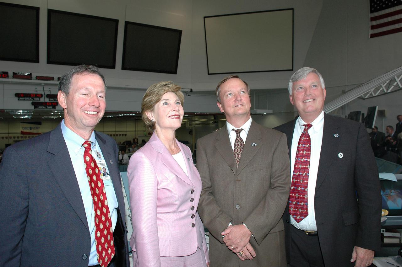 KENNEDY SPACE CENTER, FLA. - In the Launch Control Center at NASA Kennedy Space Center, NASA Administrator Mike Griffin, First Lady Laura Bush, Shuttle Launch Director Mike Leinbach and Center Director Jim Kennedy watch a replay of the successful launch of Space Shuttle Discovery on Return to Flight mission STS-114.  She is only the third First Lady to witness a Space Shuttle launch at KSC. On this mission to the International Space Station the crew will perform inspections on-orbit for the first time of all of the Reinforced Carbon-Carbon (RCC) panels on the leading edge of the wings and the Thermal Protection System tiles using the new Canadian-built Orbiter Boom Sensor System and the data from 176 impact and temperature sensors. Mission Specialists will also practice repair techniques on RCC and tile samples during a spacewalk in the payload bay.  During two additional spacewalks, the crew will install the External Stowage Platform-2, equipped with spare part assemblies, and a replacement Control Moment Gyroscope contained in the Lightweight Multi-Purpose Experiment Support Structure. The 12-day mission is expected to end with touchdown at the Shuttle Landing Facility on Aug. 7.
