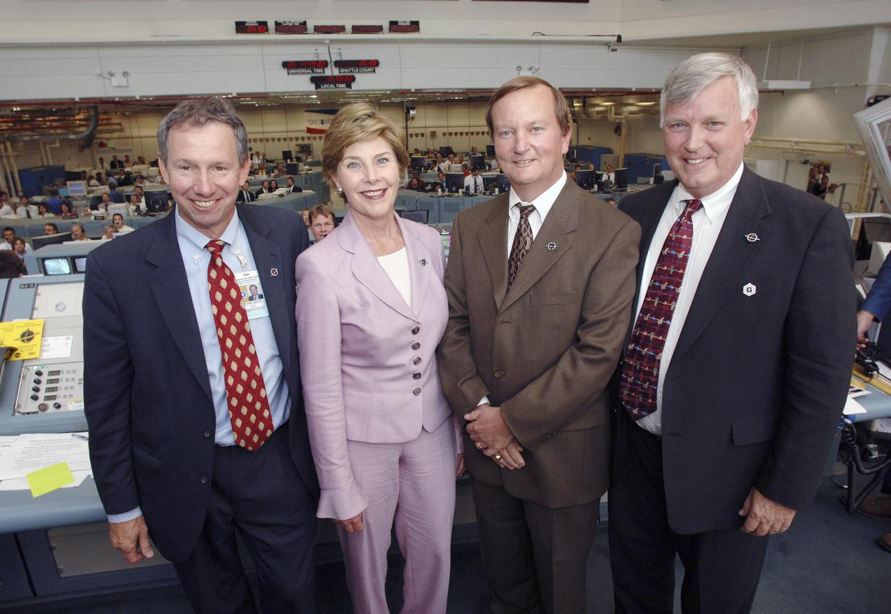 KENNEDY SPACE CENTER, FLA. - In the Launch Control Center at NASA Kennedy Space Center, NASA Administrator Mike Griffin, First Lady Laura Bush, Shuttle Launch Director Mike Leinbach and Center Director Jim Kennedy pose for a photograph.  Mrs. Bush witnessed the historic launch of Space Shuttle Discovery on Return to Flight mission STS-114.  She is only the third First Lady to witness a Space Shuttle launch at KSC.  On this mission to the International Space Station the crew will perform inspections on-orbit for the first time of all of the Reinforced Carbon-Carbon (RCC) panels on the leading edge of the wings and the Thermal Protection System tiles using the new Canadian-built Orbiter Boom Sensor System and the data from 176 impact and temperature sensors. Mission Specialists will also practice repair techniques on RCC and tile samples during a spacewalk in the payload bay.  During two additional spacewalks, the crew will install the External Stowage Platform-2, equipped with spare part assemblies, and a replacement Control Moment Gyroscope contained in the Lightweight Multi-Purpose Experiment Support Structure. The 12-day mission is expected to end with touchdown at the Shuttle Landing Facility on Aug. 7. (Photo Credit: Bill Ingalls)