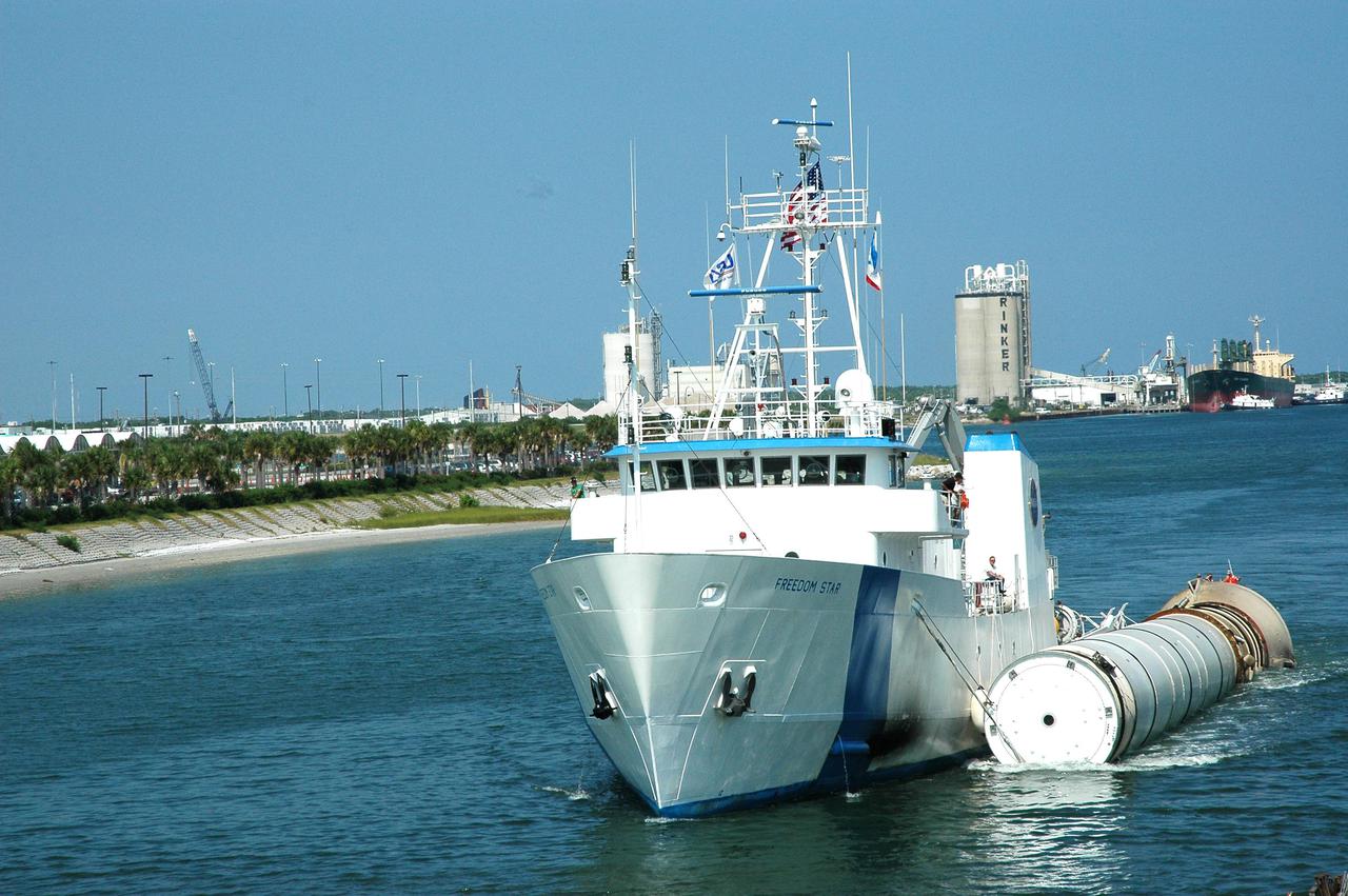 KENNEDY SPACE CENTER, FLA. - The solid rocket booster recovery ship Freedom Star travels through Port Canaveral with a spent solid rocket booster (SRB) from the STS-114 launch on July 26 in tow.  The SRBs are the largest solid propellant motors ever flown and the first designed for reuse. After a Shuttle is launched, the SRBs are jettisoned at two minutes, seven seconds into the flight. At six minutes and 44 seconds after liftoff, the spent SRBs, weighing about 165,000 lb., have slowed their descent speed to about 62 mph and splashdown takes place in a predetermined area. They are retrieved from the Atlantic Ocean by special recovery vessels and returned for refurbishment and eventual reuse on future Shuttle flights. Once at Hangar AF, the SRBs are unloaded onto a hoisting slip and mobile gantry cranes lift them onto tracked dollies where they are safed and undergo their first washing.