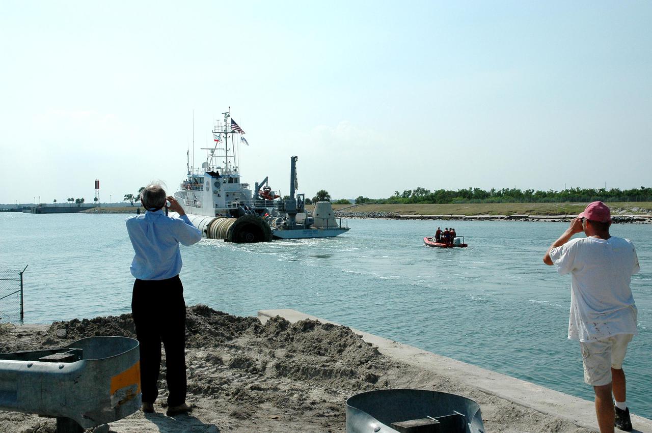 KENNEDY SPACE CENTER, FLA. - Photographers capture the solid rocket booster recovery ship Freedom Star, with a spent solid rocket booster (SRB) from the STS-114 launch on July 26 in tow, as it makes it way through Port Canaveral to Hangar AF on the Cape Canaveral Air Force Station.  The SRBs are the largest solid propellant motors ever flown and the first designed for reuse. After a Shuttle is launched, the SRBs are jettisoned at two minutes, seven seconds into the flight. At six minutes and 44 seconds after liftoff, the spent SRBs, weighing about 165,000 lb., have slowed their descent speed to about 62 mph and splashdown takes place in a predetermined area. They are retrieved from the Atlantic Ocean by special recovery vessels and returned for refurbishment and eventual reuse on future Shuttle flights. Once at Hangar AF, the SRBs are unloaded onto a hoisting slip and mobile gantry cranes lift them onto tracked dollies where they are safed and undergo their first washing.