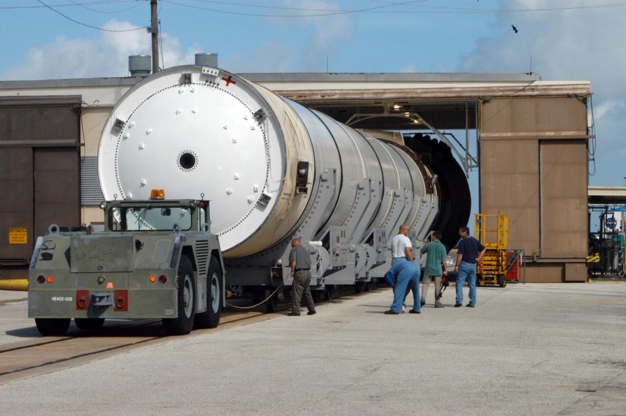 KENNEDY SPACE CENTER, FLA. -  Workers in Hangar AF at Cape Canaveral Air Force Station take a look at one of the spent Solid Rocket Boosters (SRBs) from the launch of Space Shuttle Discovery July 26 on Return to Flight mission STS-114.  The SRBs are the largest solid propellant motors ever flown and the first designed for reuse. After a Shuttle is launched, the SRBs are jettisoned at two minutes, seven seconds into the flight. At six minutes and 44 seconds after liftoff, the spent SRBs, weighing about 165,000 lb., have slowed their descent speed to about 62 mph and splashdown takes place in a predetermined area. They are retrieved from the Atlantic Ocean by special recovery vessels and returned for refurbishment and eventual reuse on future Shuttle flights. Once at Hangar AF, the SRBs are unloaded onto a hoisting slip and mobile gantry cranes lift them onto tracked dollies where they are safed and undergo their first washing.