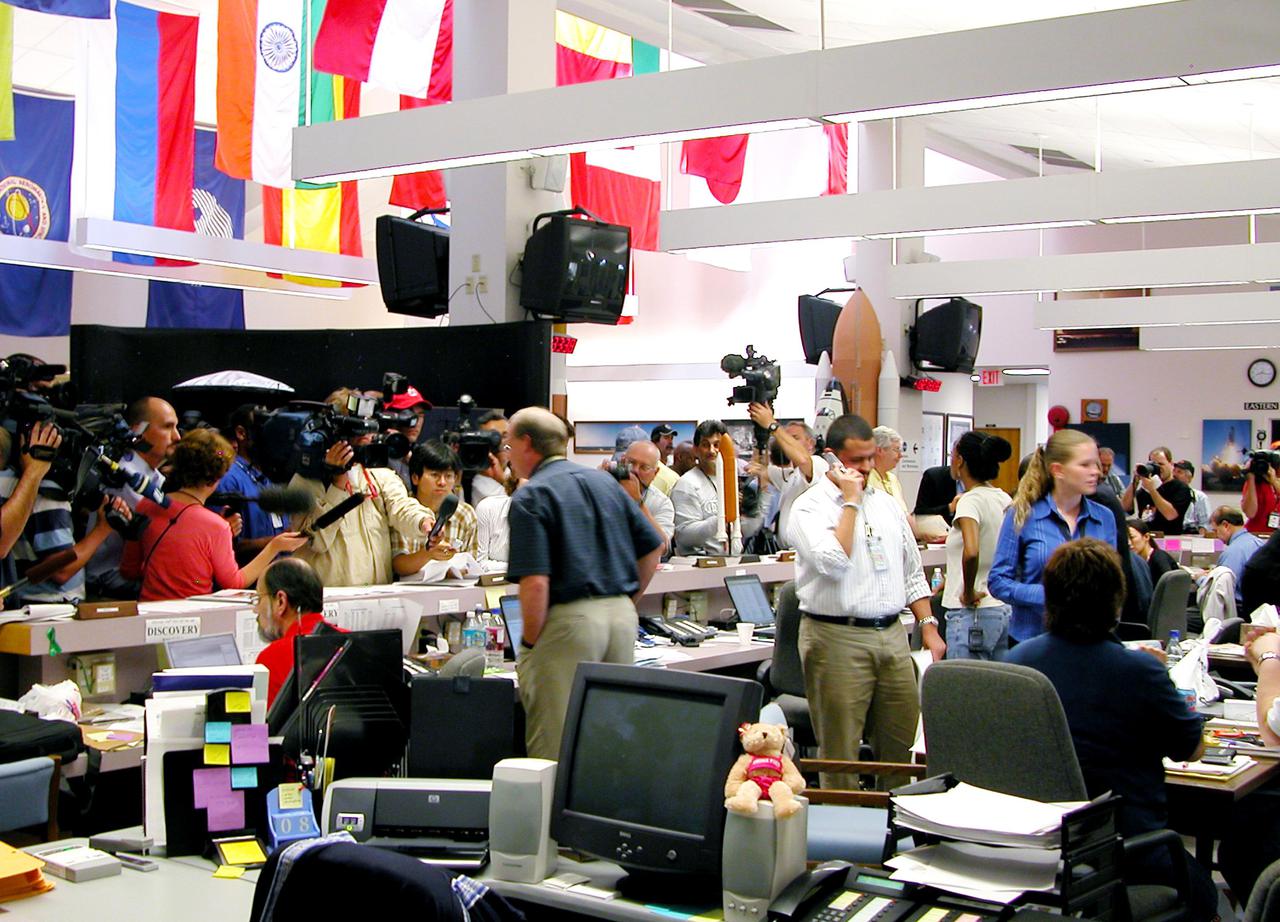 KENNEDY SPACE CENTER, FLA. - Gathered in the NASA News Center, the media ask Public Information Officer Bruce Buckingham about the landing of Space Shuttle Discovery at Edwards Air Force Base in California. Due to weather concerns, the landing was deferred to the alternate site. The 13-day, 21-hour Return to Flight STS-114 mission ended on Runway 22 at 8:11:22 a.m. EDT with Mission Commander Eileen Collins on the controls. Discovery spent two weeks in space, where the crew demonstrated new methods to inspect and repair the Shuttle in orbit. The crew also delivered supplies, outfitted and performed maintenance on the International Space Station. A number of these tasks were conducted during three spacewalks. Photo credit: NASA_Debbie Kiger
