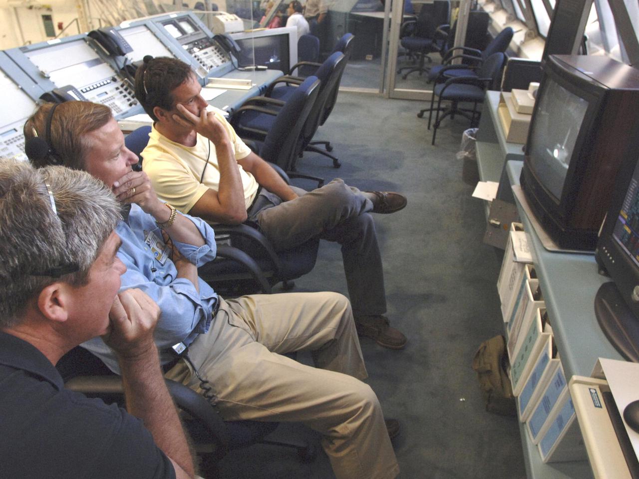 KENNEDY SPACE CENTER, FLA. - In the Firing Room of the Launch Control Center at NASA Kennedy Space Center, Space Shuttle Program Manager Bill Parsons, Shuttle Launch Director Mike Leinbach and Assistant Launch Director Doug Lyons applaud the successful landing of Space Shuttle Discovery on Runway 22 at Edwards Air Force Base in California. The landing was deferred to Edwards due to weather concerns at KSC. Landing time was 8:11:22 a.m. EDT, guided by Mission Commander Eileen Collins. Discovery spent two weeks in space on Return to Flight mission STS-114, where the crew demonstrated new methods to inspect and repair the Shuttle in orbit. The crew also delivered supplies, outfitted and performed maintenance on the International Space Station. A number of these tasks were conducted during three spacewalks. (Photo Credit: NASA_Bill Ingalls)