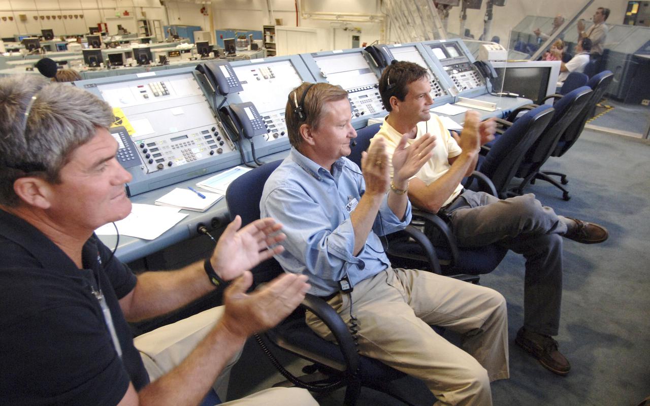KENNEDY SPACE CENTER, FLA. - In the Firing Room of the Launch Control Center at NASA Kennedy Space Center, Space Shuttle Program Manager Bill Parsons, Shuttle Launch Director Mike Leinbach and Assistant Launch Director Doug Lyons applaud the successful landing of Space Shuttle Discovery on Runway 22 at Edwards Air Force Base in California. The landing was deferred to Edwards due to weather concerns at KSC. Landing time was 8:11:22 a.m. EDT, guided by Mission Commander Eileen Collins. Discovery spent two weeks in space on Return to Flight mission STS-114, where the crew demonstrated new methods to inspect and repair the Shuttle in orbit. The crew also delivered supplies, outfitted and performed maintenance on the International Space Station. A number of these tasks were conducted during three spacewalks. (Photo Credit: NASA_Bill Ingalls)