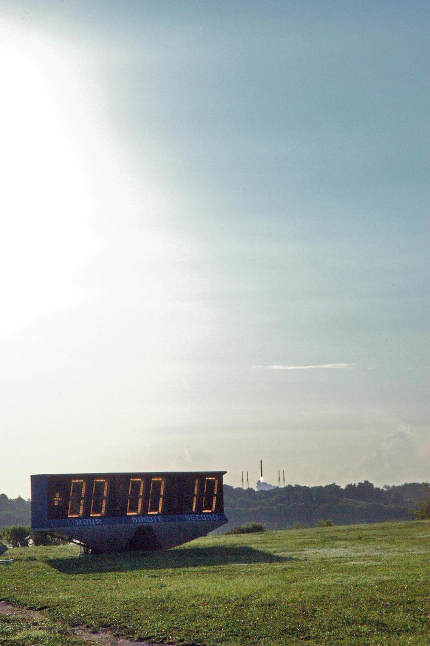 KENNEDY SPACE CENTER, FLA. - Seen on the horizon just past the NASA News Center’s countdown clock, NASA's Mars Reconnaissance Orbiter (MRO) launches at 7:43 a.m. EDT atop a Lockheed Martin Atlas V rocket from Launch Complex 41 at Cape Canaveral Air Force Station in Florida. All systems performed nominally for NASA's first Atlas V launch. The spacecraft will arrive at Mars in March 2006. Once in orbit around Mars, various instruments on the MRO will convey detailed observations of the Martian surface, subsurface and atmosphere. Researchers will use the data to study the history and distribution of Martian water. Learning more about what has happened to the water will focus searches for possible past or present Martian life. Observations by the orbiter will also support future Mars missions by examining potential landing sites and providing a communications relay between the Martian surface and Earth.