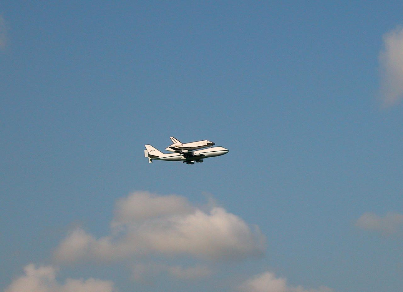 KENNEDY SPACE CENTER, FLA. --  Space Shuttle Discovery, atop a modified Boeing 747 Shuttle Carrier Aircraft (SCA), flies over Launch Complex 39 at Kennedy Space Center on its final approach to runway 15 at the Shuttle Landing Facility (SLF).  Landing was at about 10:00 a.m. EDT. The cross-country ferry flight became necessary when two days of unfavorable weather conditions at KSC forced Discovery to land on runway 22 at Edwards Air Force Base, Calif., on Aug. 9 following mission STS-114. The SCA and Discovery will be towed to the Mate_Demate Device at the SLF where a crane will lift Discovery from the SCA and place it on solid ground. Discovery will then be towed to the Orbiter Processing Facility where preparations will begin for its next flight, STS-121.