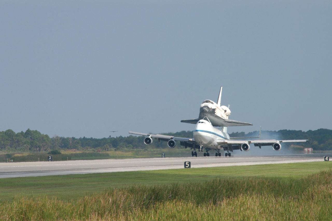 KENNEDY SPACE CENTER, FLA. -  Space Shuttle Discovery, atop a modified Boeing 747 Shuttle Carrier Aircraft (SCA),  lands on runway 15 at NASA Kennedy Space Center's Shuttle Landing Facility (SLF) at about 10:00 a.m. EDT. The cross-country ferry flight became necessary when two days of unfavorable weather conditions at KSC forced Discovery to land on runway 22 at Edwards Air Force Base, Calif., on Aug. 9 following mission STS-114. On the return trip, stops were made at Altus Air Force Base, Okla., and Barksdale Air Force Base, La., where Discovery stayed for two nights.  The SCA and Discovery will be towed to the Mate_Demate Device at the SLF where a crane will lift Discovery from the SCA and place it on solid ground. Discovery will then be towed to the Orbiter Processing Facility where preparations will begin for its next flight, STS-121.