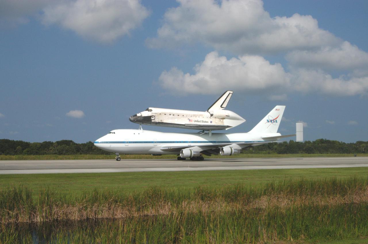 KENNEDY SPACE CENTER, FLA. -  Space Shuttle Discovery, atop a modified Boeing 747 Shuttle Carrier Aircraft (SCA),  lands on runway 15 at NASA Kennedy Space Center's Shuttle Landing Facility (SLF) at about 10:00 a.m. EDT. The cross-country ferry flight became necessary when two days of unfavorable weather conditions at KSC forced Discovery to land on runway 22 at Edwards Air Force Base, Calif., on Aug. 9 following mission STS-114. On the return trip, stops were made at Altus Air Force Base, Okla., and Barksdale Air Force Base, La., where Discovery stayed for two nights.  The SCA and Discovery will be towed to the Mate_Demate Device at the SLF where a crane will lift Discovery from the SCA and place it on solid ground. Discovery will then be towed to the Orbiter Processing Facility where preparations will begin for its next flight, STS-121.