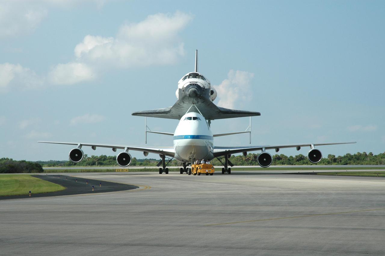KENNEDY SPACE CENTER, FLA. -  Space Shuttle Discovery, atop a modified Boeing 747 Shuttle Carrier Aircraft (SCA), is towed to the Mate_Demate Device (MDD) at NASA Kennedy Space Center's Shuttle Landing Facility (SLF) following touchdown on runway 15 at about 10:00 a.m. EDT. The cross-country ferry flight became necessary when two days of unfavorable weather conditions at KSC forced Discovery to land on runway 22 at Edwards Air Force Base, Calif., on Aug. 9 following mission STS-114. On the return trip, stops were made at Altus Air Force Base, Okla., and Barksdale Air Force Base, La., where Discovery stayed for two nights. A crane on the MDD will lift Discovery from the SCA and place it on solid ground. Discovery will then be towed to the Orbiter Processing Facility where preparations will begin for its next flight, STS-121.