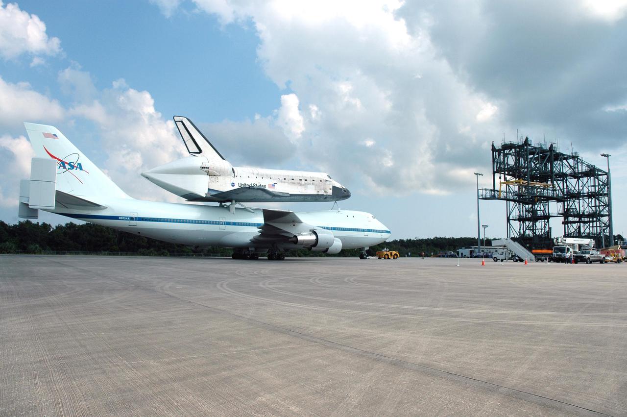 KENNEDY SPACE CENTER, FLA. -  Space Shuttle Discovery, atop a modified Boeing 747 Shuttle Carrier Aircraft (SCA), is towed to the Mate_Demate Device (MDD), at right, at NASA Kennedy Space Center's Shuttle Landing Facility (SLF) following touchdown on runway 15 at about 10:00 a.m. EDT. The cross-country ferry flight became necessary when two days of unfavorable weather conditions at KSC forced Discovery to land on runway 22 at Edwards Air Force Base, Calif., on Aug. 9 following mission STS-114. On the return trip, stops were made at Altus Air Force Base, Okla., and Barksdale Air Force Base, La., where Discovery stayed for two nights.  A crane on the MDD will lift Discovery from the SCA and place it on solid ground. Discovery will then be towed to the Orbiter Processing Facility where preparations will begin for its next flight, STS-121.