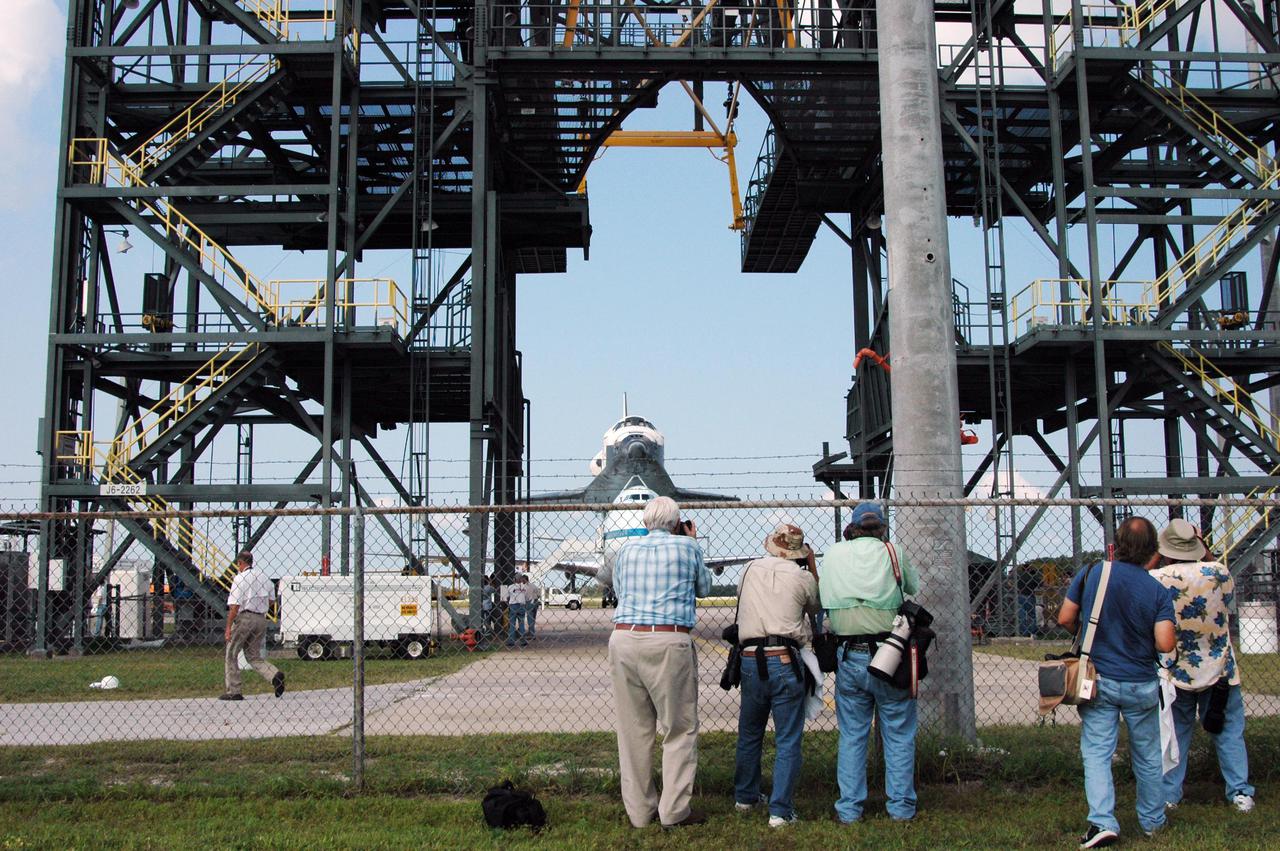 KENNEDY SPACE CENTER, FLA. - News media photographers capture the approach of Space Shuttle Discovery, atop a modified Boeing 747 Shuttle Carrier Aircraft (SCA), as it is towed to the Mate_Demate Device (MDD) at the Kennedy Space Center (KSC) Shuttle Landing Facility (SLF). Discovery touched down on runway 15 at the SLF at about 10:00 a.m. EDT. The cross-country ferry flight became necessary when two days of unfavorable weather conditions at KSC forced Discovery to land on runway 22 at Edwards Air Force Base, Calif., on Aug. 9 following mission STS-114. On the return trip, stops were made at Altus Air Force Base, Okla., and Barksdale Air Force Base, La., where Discovery stayed for two nights. A crane on the MDD will lift Discovery from the SCA and place it on solid ground. Discovery will then be towed to the Orbiter Processing Facility where preparations will begin for its next flight, STS-121.