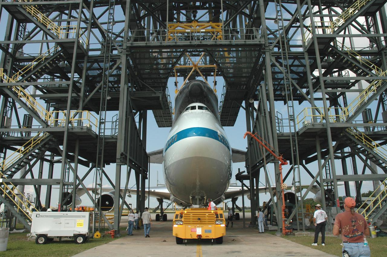 KENNEDY SPACE CENTER, FLA. -  The Shuttle Carrier Aircraft, a modified Boeing 747, with the orbiter Discovery on top is towed into the mate_demate device at NASA Kennedy Space Center’s Shuttle Landing Facility.  Discovery was returned to Kennedy Space Center on a ferry flight from Edwards Air Force Base in California, where it landed Aug. 9 after 13 days in space on mission STS-114.  In the mate_demate device, a horizontal structure mounted at the 80-foot level between two towers controls and guides a large lift beam that attaches to the orbiter to raise and lower it.  Once Discovery is lifted off the back of the SCA, the 747 can then roll away and the orbiter will be lowered to the ground.  It will then be towed from the SLF to the Orbiter Processing Facility.  Once inside the OPF, the payload bay doors will be opened and the MPLM Raffaello brought back from the International Space Station will be unloaded and transferred to the Space Station Processing Facility.  This concludes mission STS-114.