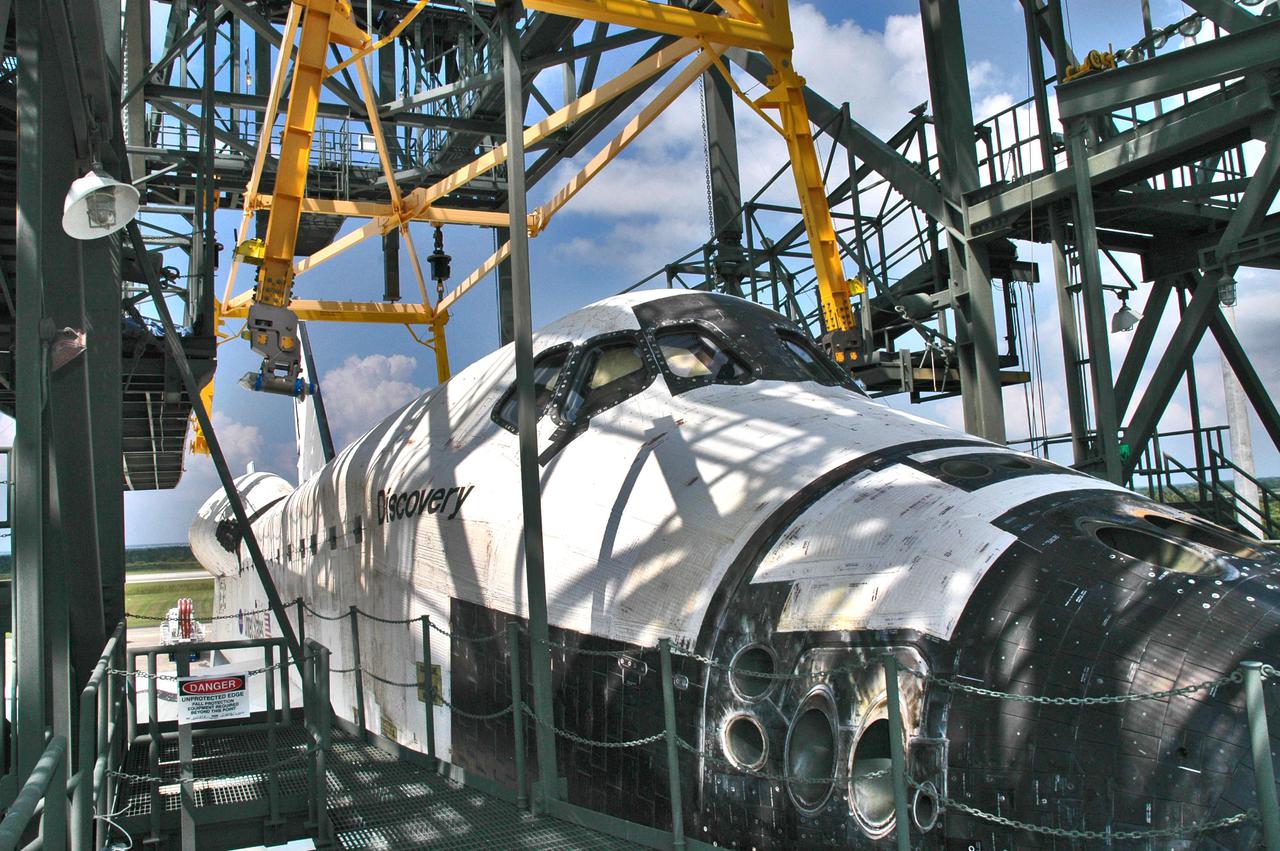KENNEDY SPACE CENTER, FLA. -  The orbiter Discovery on top of the Shuttle Carrier Aircraft, a modified Boeing 747, is in place under the mate_demate device at NASA Kennedy Space Center’s Shuttle Landing Facility.  Discovery was returned to Kennedy Space Center on a ferry flight from Edwards Air Force Base in California, where it landed Aug. 9 after 13 days in space on mission STS-114.  In the mate_demate device, a horizontal structure mounted at the 80-foot level between two towers controls and guides a large lift beam that attaches to the orbiter to raise and lower it.  Once Discovery is lifted off the back of the SCA, the 747 can then roll away and the orbiter will be lowered to the ground.  It will then be towed from the SLF to the Orbiter Processing Facility.  Once inside the OPF, the payload bay doors will be opened and the MPLM Raffaello brought back from the International Space Station will be unloaded and transferred to the Space Station Processing Facility.  This concludes mission STS-114.