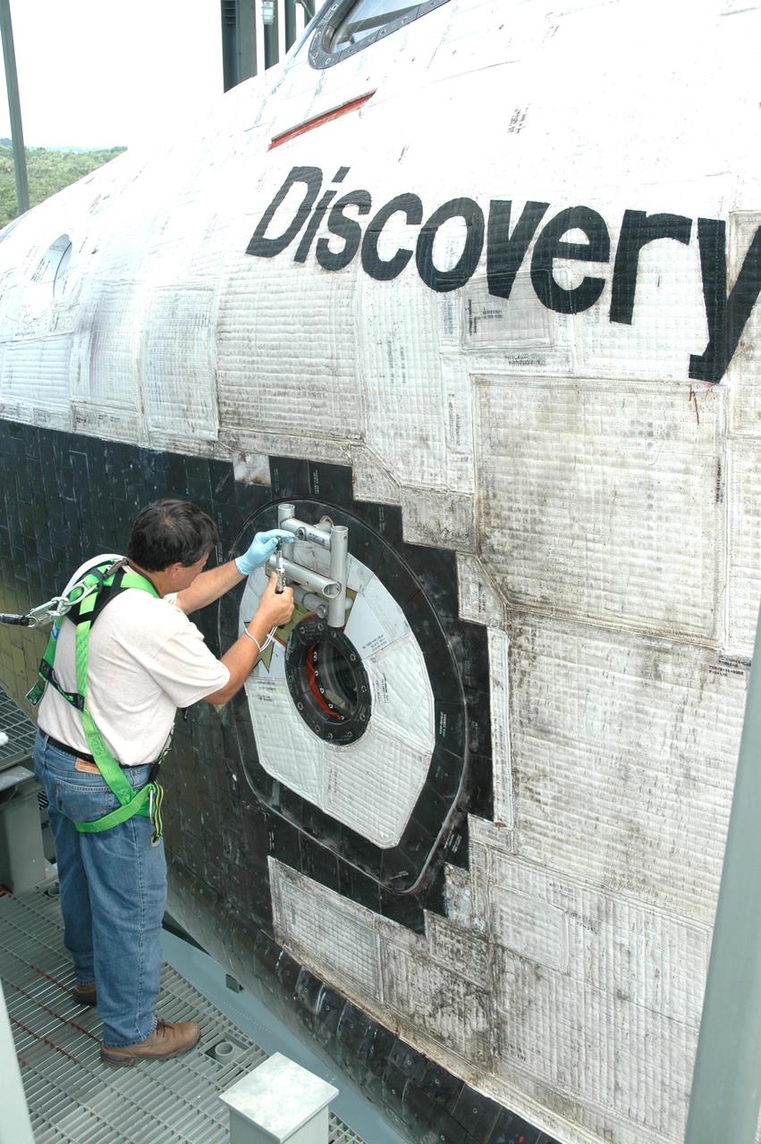 KENNEDY SPACE CENTER, FLA. -  At NASA Kennedy Space Center’s Shuttle Landing Facility, a worker begins preparing the orbiter Discovery for demating.   Discovery was returned to Kennedy Space Center on a ferry flight from Edwards Air Force Base in California, where it landed Aug. 9 after 13 days in space on mission STS-114.  In the mate_demate device, a horizontal structure mounted at the 80-foot level between two towers controls and guides a large lift beam that attaches to the orbiter to raise and lower it.  Once Discovery is lifted off the back of the SCA, the 747 can then roll away and the orbiter will be lowered to the ground.  It will then be towed from the SLF to the Orbiter Processing Facility.  Once inside the OPF, the payload bay doors will be opened and the MPLM Raffaello brought back from the International Space Station will be unloaded and transferred to the Space Station Processing Facility.  This concludes mission STS-114.