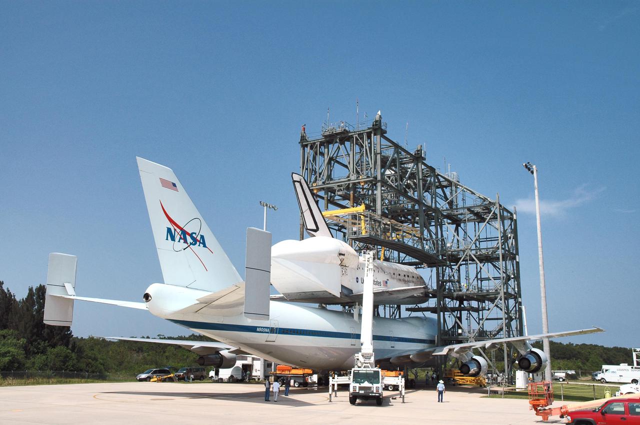 KENNEDY SPACE CENTER, FLA. - At NASA Kennedy Space Center’s Shuttle Landing Facility, the Shuttle Carrier Aircraft, a modified Boeing 747, and orbiter Discovery on top, remain in the mate_demate device while Discovery is prepared for demating. Discovery was returned to Kennedy Space Center on a ferry flight from Edwards Air Force Base in California, where it landed Aug. 9 after 13 days in space on mission STS-114. In the mate_demate device, a horizontal structure mounted at the 80-foot level between two towers controls and guides a large lift beam that attaches to the orbiter to raise and lower it. Once Discovery is lifted off the back of the SCA, the 747 can then roll away and the orbiter will be lowered to the ground. It will then be towed from the SLF to the Orbiter Processing Facility. Once inside the OPF, the payload bay doors will be opened and the MPLM Raffaello brought back from the International Space Station will be unloaded and transferred to the Space Station Processing Facility. This concludes mission STS-114.
