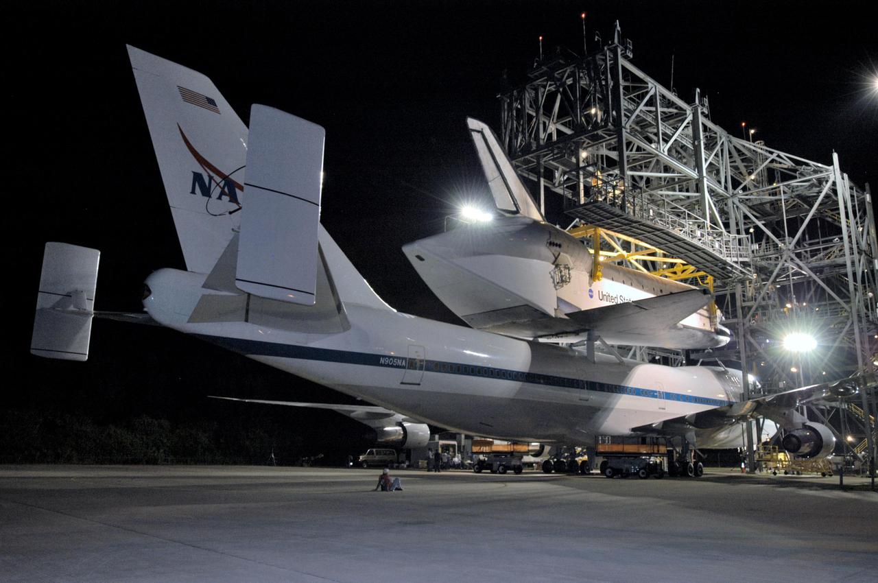 KENNEDY SPACE CENTER, FLA. - Near midnight, lights from the mate_demate device at NASA Kennedy Space Center’s Shuttle Landing Facility shine on the orbiter Discovery on top of the Shuttle Carrier Aircraft, a modified Boeing 747. Discovery was returned to Kennedy Space Center on a ferry flight from Edwards Air Force Base in California, where it landed Aug. 9 after 13 days in space on mission STS-114. In the mate_demate device, a horizontal structure mounted at the 80-foot level between two towers controls and guides a large lift beam that attaches to the orbiter to raise and lower it. Once Discovery is lifted off the back of the SCA, the 747 can then roll away and the orbiter will be lowered to the ground. It will then be towed from the SLF to the Orbiter Processing Facility. Once inside the OPF, the payload bay doors will be opened and the MPLM Raffaello brought back from the International Space Station will be unloaded and transferred to the Space Station Processing Facility. This concludes mission STS-114.