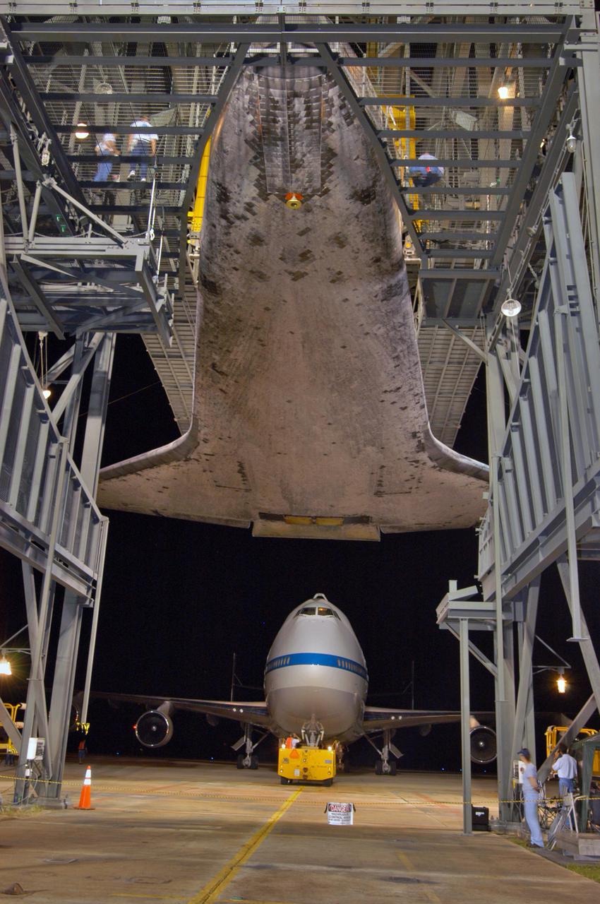 KENNEDY SPACE CENTER, FLA. -  In the early morning hours at NASA Kennedy Space Center’s Shuttle Landing Facility, the orbiter Discovery is suspended within the mate_demate device after the Shuttle Carrier Aircraft, a modified Boeing 747, has rolled away from beneath it.  Discovery was returned to Kennedy Space Center on a ferry flight from Edwards Air Force Base in California, where it landed Aug. 9 after 13 days in space on mission STS-114.  In the mate_demate device, a horizontal structure mounted at the 80-foot level between two towers controls and guides a large lift beam that attaches to the orbiter to raise and lower it.  The orbiter will be lowered to the ground and then be towed to the Orbiter Processing Facility.  Once inside the OPF, the payload bay doors will be opened and the MPLM Raffaello brought back from the International Space Station will be unloaded and transferred to the Space Station Processing Facility.  This concludes mission STS-114.