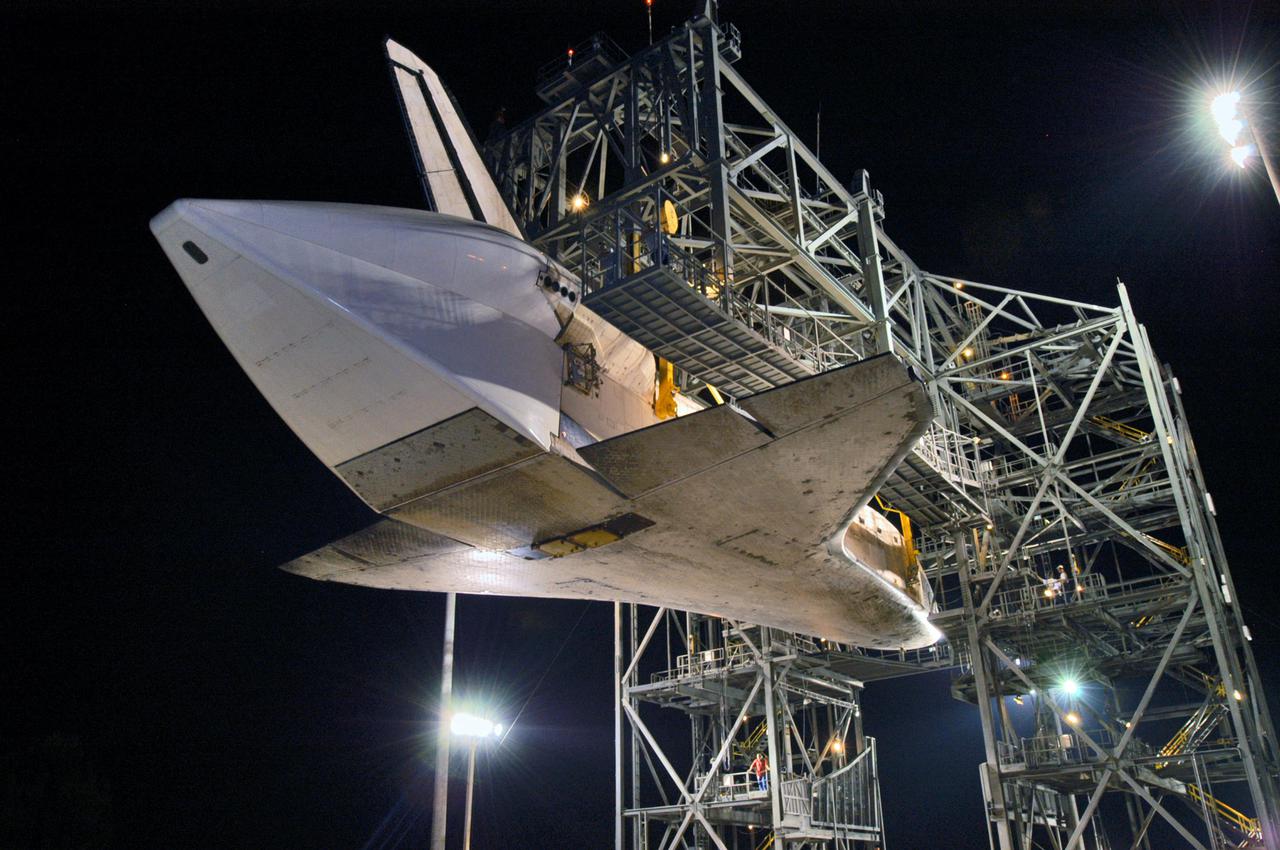 KENNEDY SPACE CENTER, FLA. - In the early morning hours at NASA Kennedy Space Center’s Shuttle Landing Facility, the orbiter Discovery is suspended within the mate_demate device after the Shuttle Carrier Aircraft, a modified Boeing 747, has rolled away from beneath it. Visible on the orbiter is the tail cone that covers the main engines during the ferry flight. Discovery was returned to Kennedy Space Center on a ferry flight from Edwards Air Force Base in California, where it landed Aug. 9 after 13 days in space on mission STS-114. In the mate_demate device, a horizontal structure mounted at the 80-foot level between two towers controls and guides a large lift beam that attaches to the orbiter to raise and lower it. The orbiter will be lowered to the ground and then be towed to the Orbiter Processing Facility. Once inside the OPF, the payload bay doors will be opened and the MPLM Raffaello brought back from the International Space Station will be unloaded and transferred to the Space Station Processing Facility. This concludes mission STS-114.