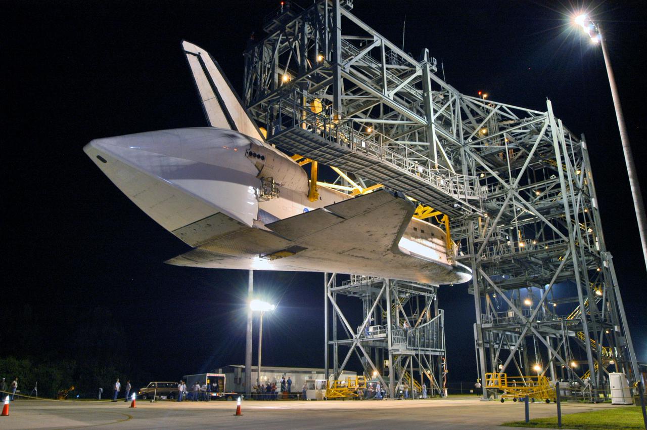 KENNEDY SPACE CENTER, FLA. -  In the early morning hours at NASA Kennedy Space Center’s Shuttle Landing Facility, the orbiter Discovery is slowly lowered toward the ground from the mate_demate device. Visible on the orbiter is the tail cone that covers the main engines during the ferry flight.   Discovery was returned to Kennedy Space Center on a ferry flight from Edwards Air Force Base in California, where it landed Aug. 9 after 13 days in space on mission STS-114.  In the mate_demate device, a horizontal structure mounted at the 80-foot level between two towers controls and guides a large lift beam that attaches to the orbiter to raise and lower it.  The orbiter will be lowered to the ground and then be towed to the Orbiter Processing Facility.  Once inside the OPF, the payload bay doors will be opened and the MPLM Raffaello brought back from the International Space Station will be unloaded and transferred to the Space Station Processing Facility.  This concludes mission STS-114.
